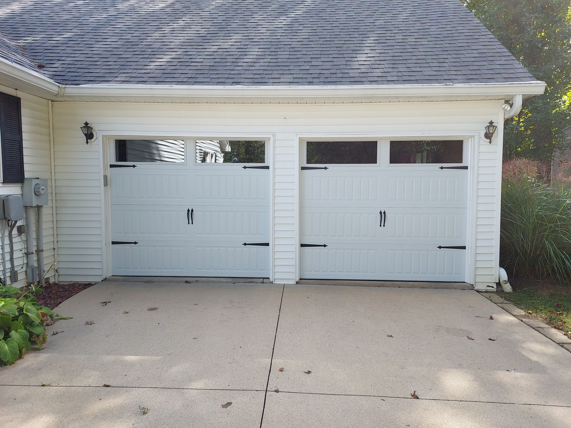 A white garage door is sitting in front of a white house.