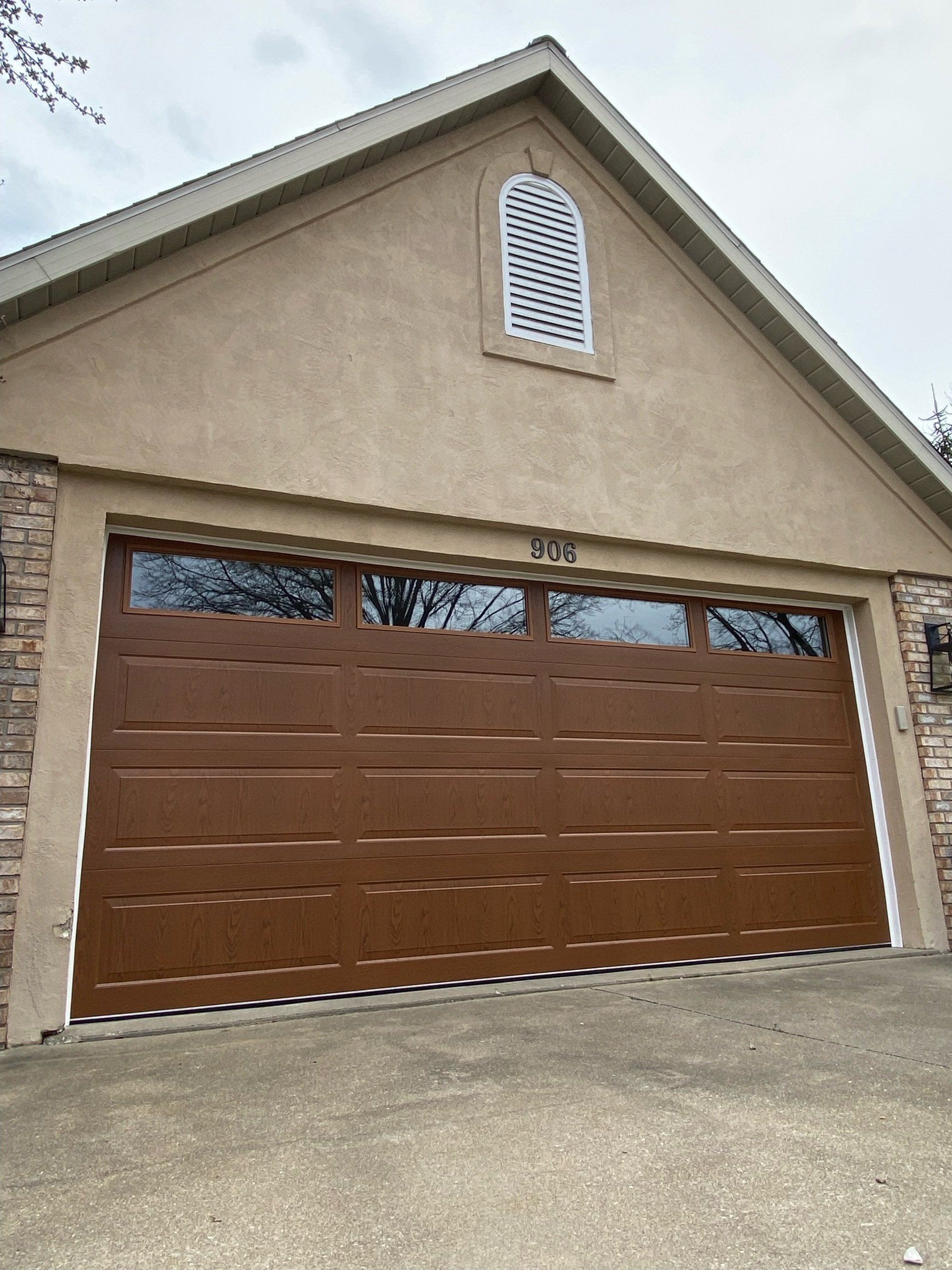 A brown garage door is on the side of a house.