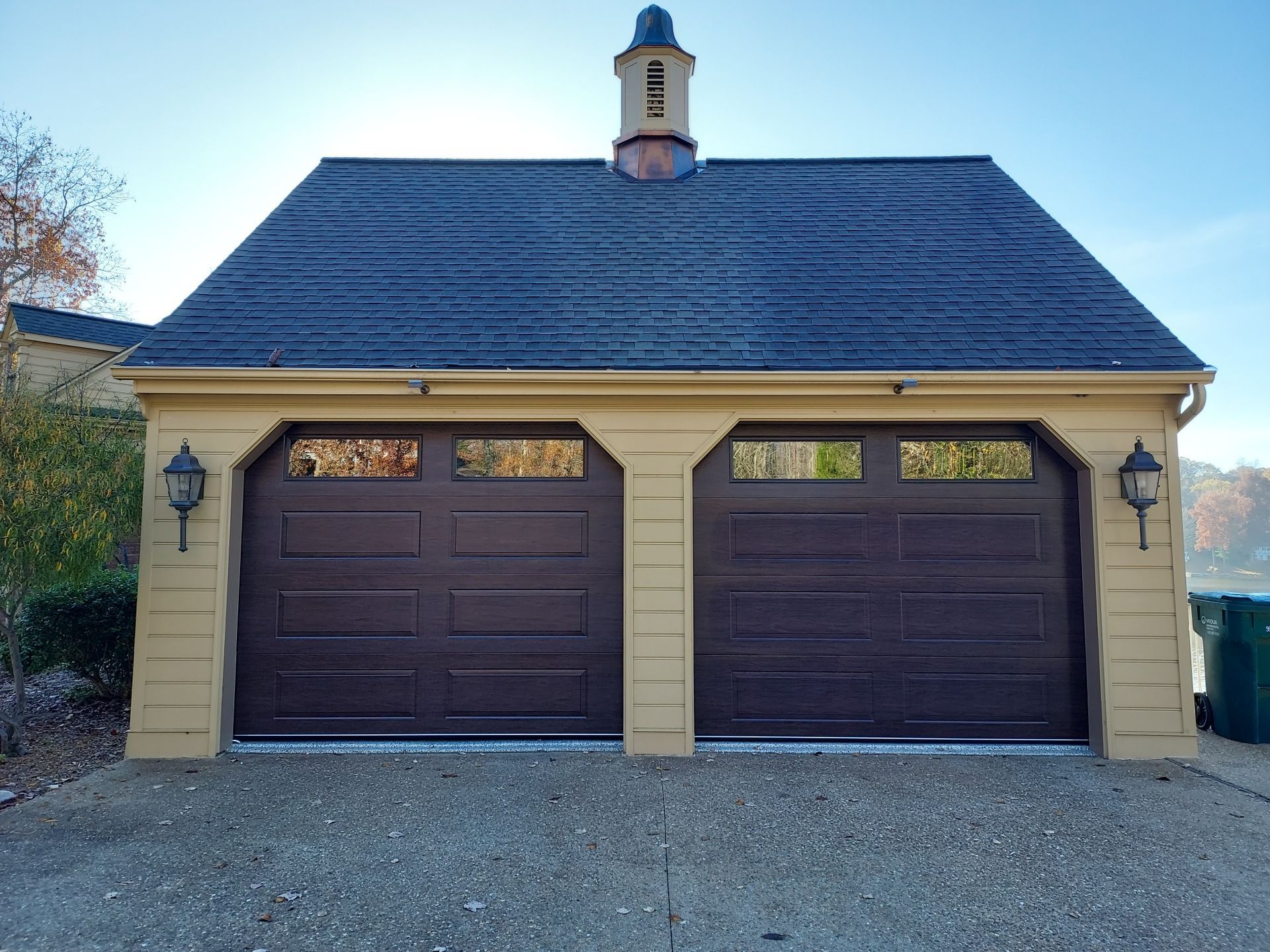 A yellow garage with brown garage doors and a black roof