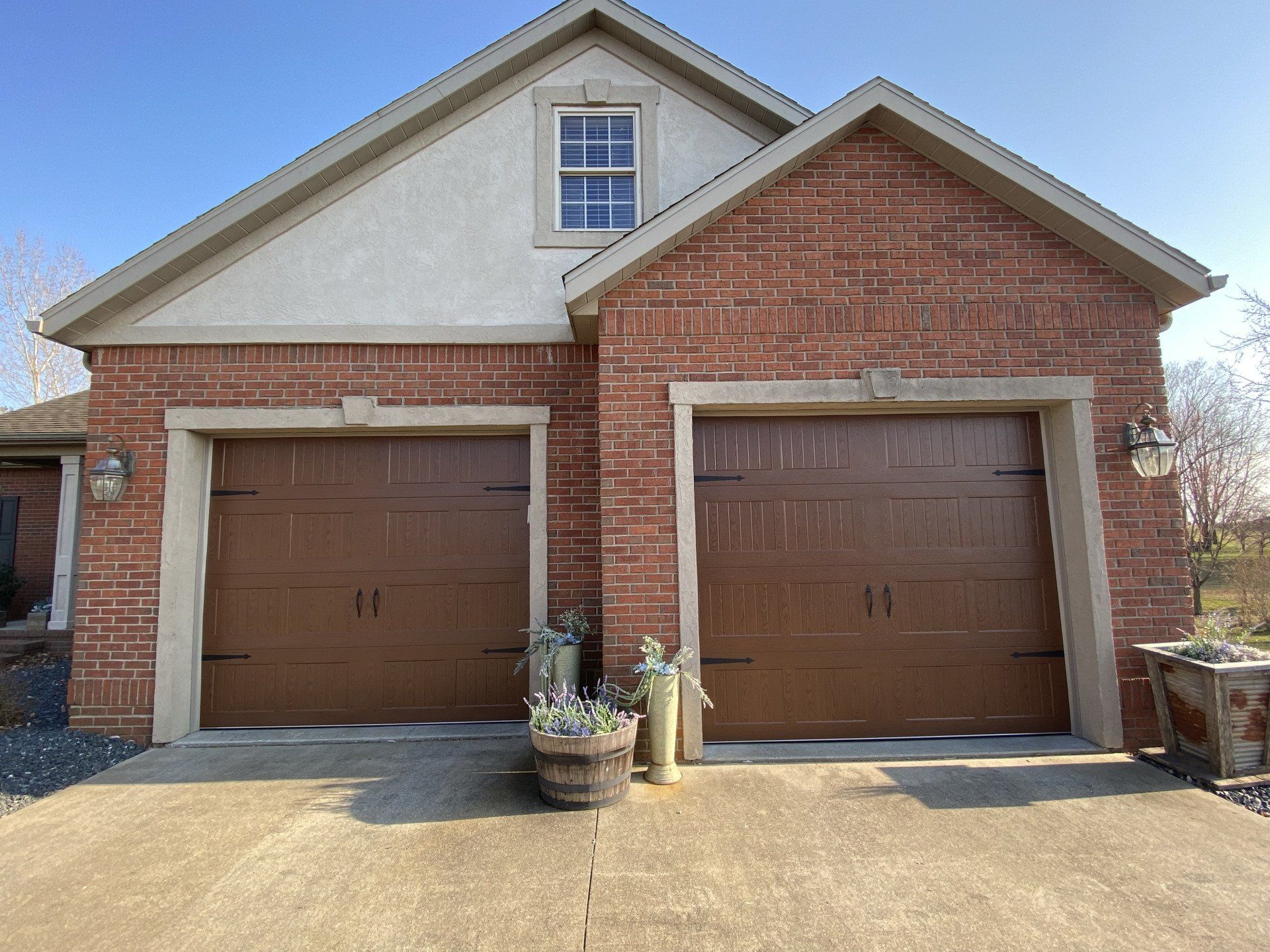 A brick house with two brown garage doors and a window.