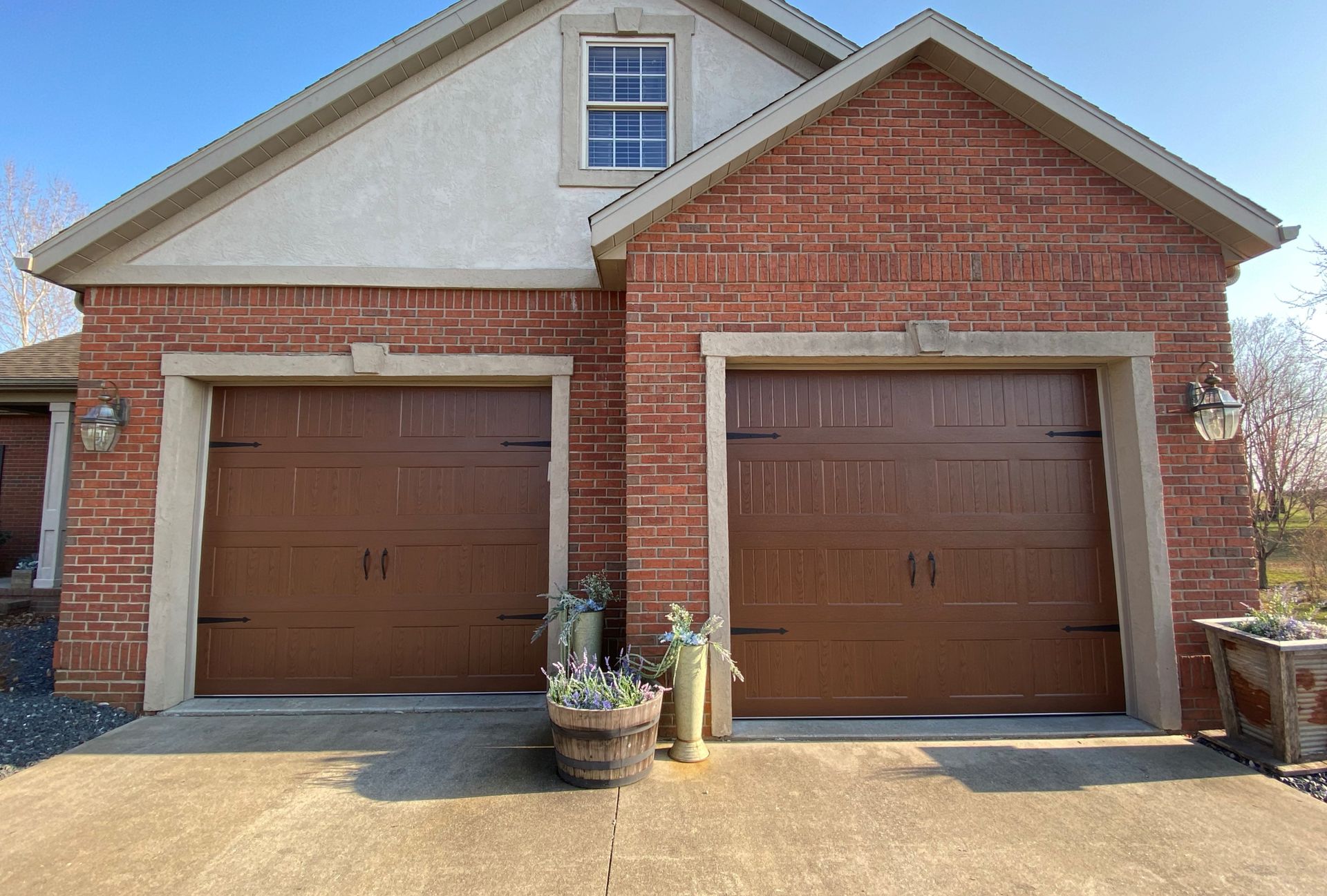 A brick house with two brown garage doors and a window.