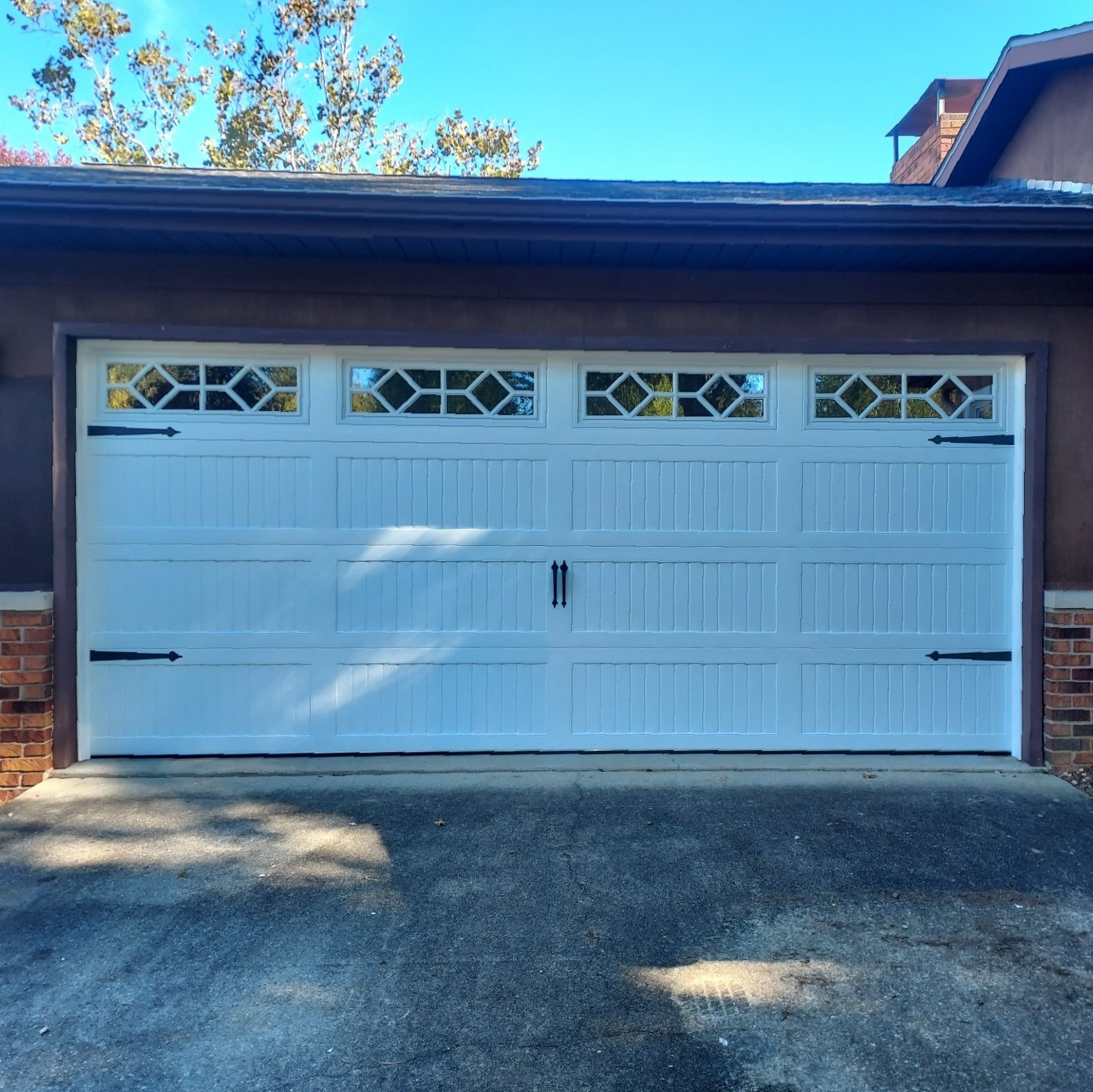 A white garage door is sitting in front of a brown house