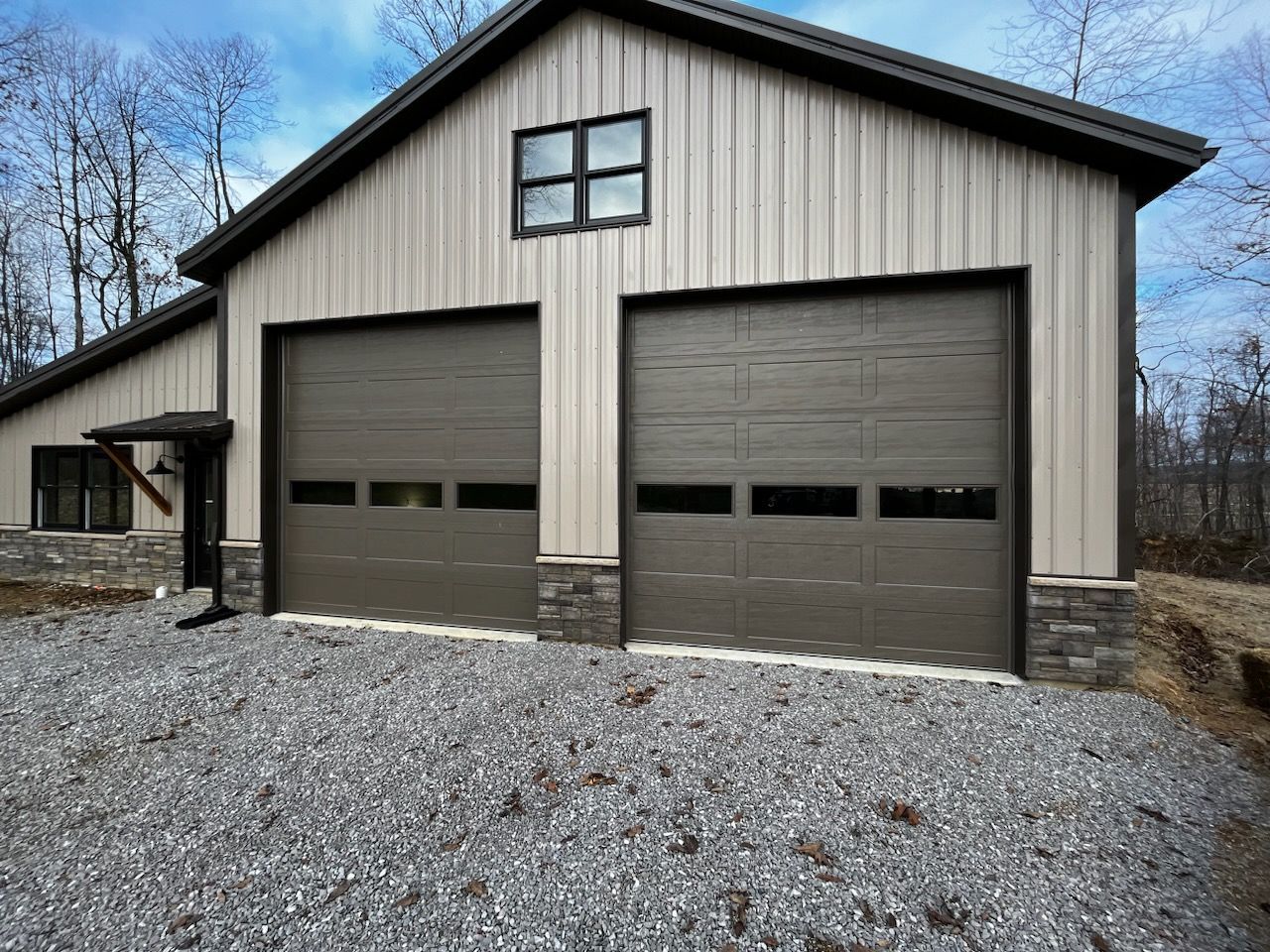 A garage with two garage doors and a window on the side of it.