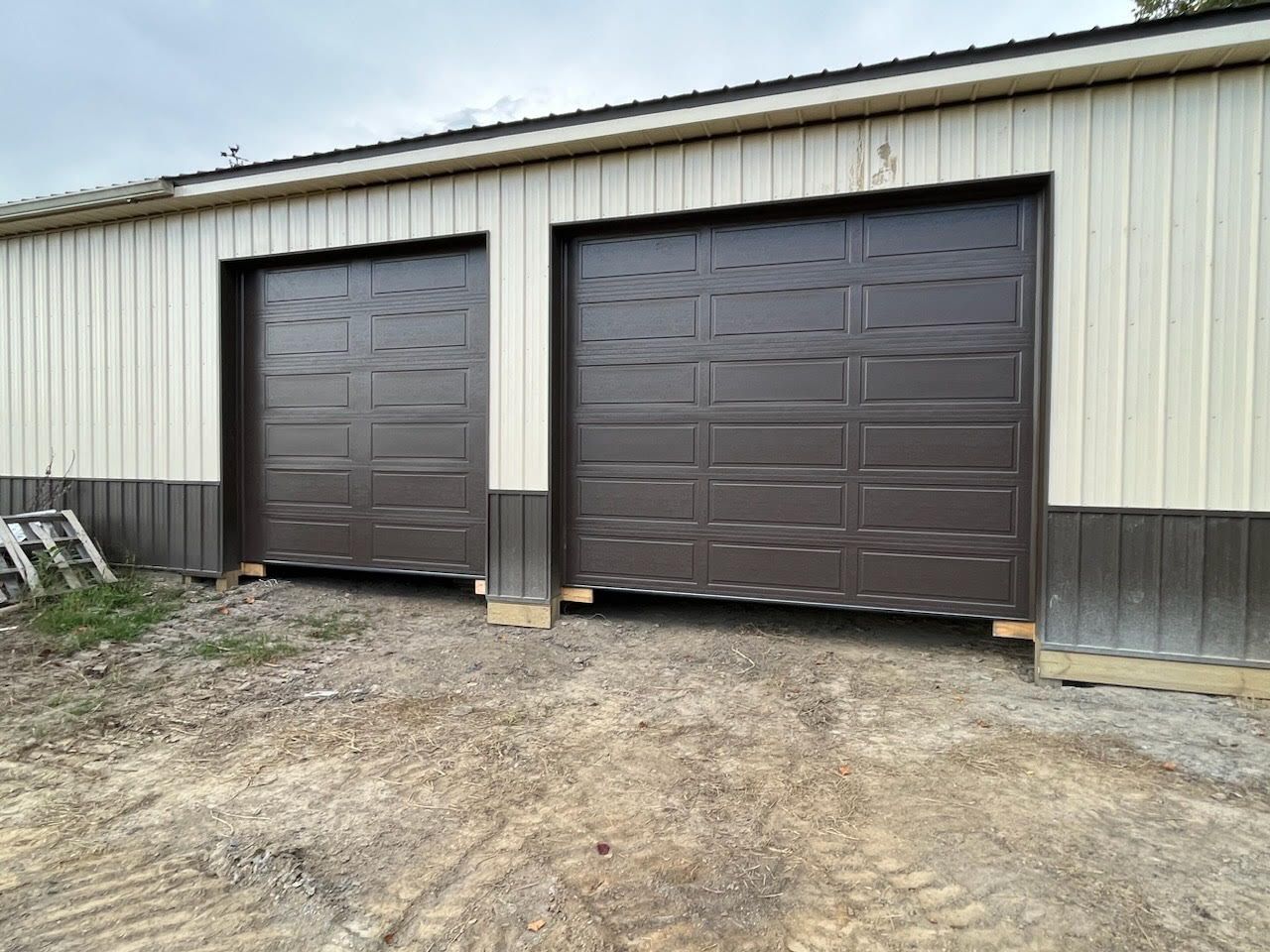 There are two garage doors on the side of a building.