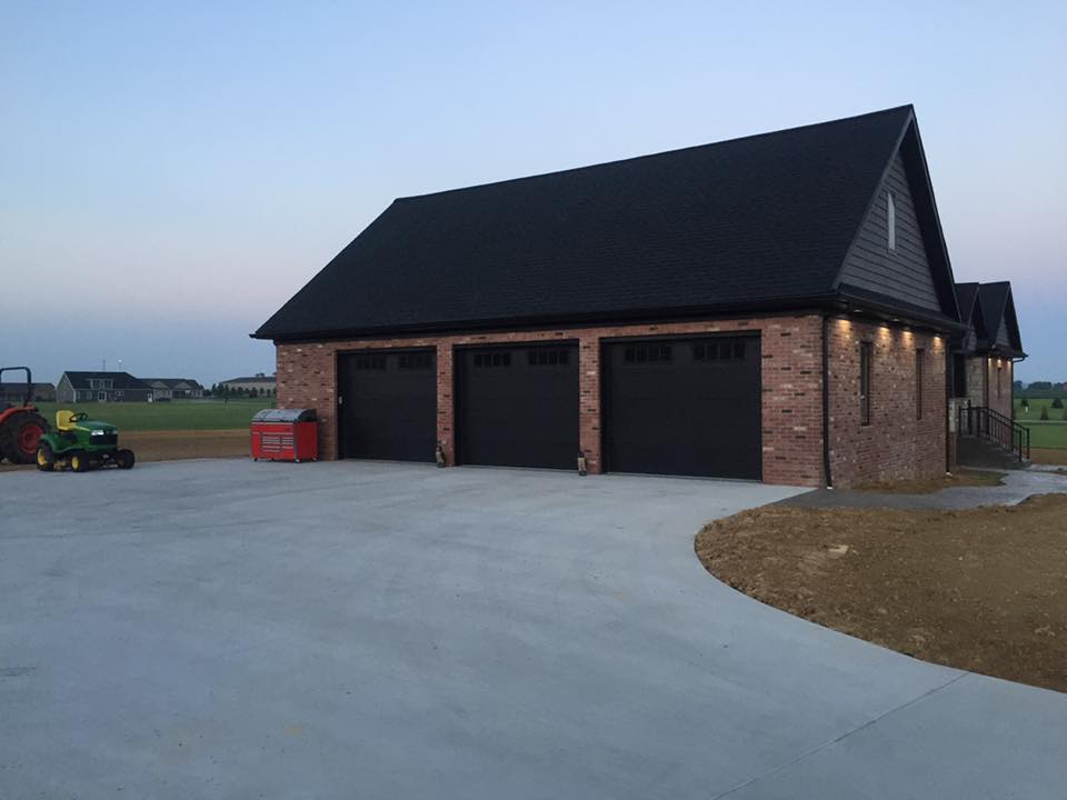 A john deere tractor is parked in front of a garage.