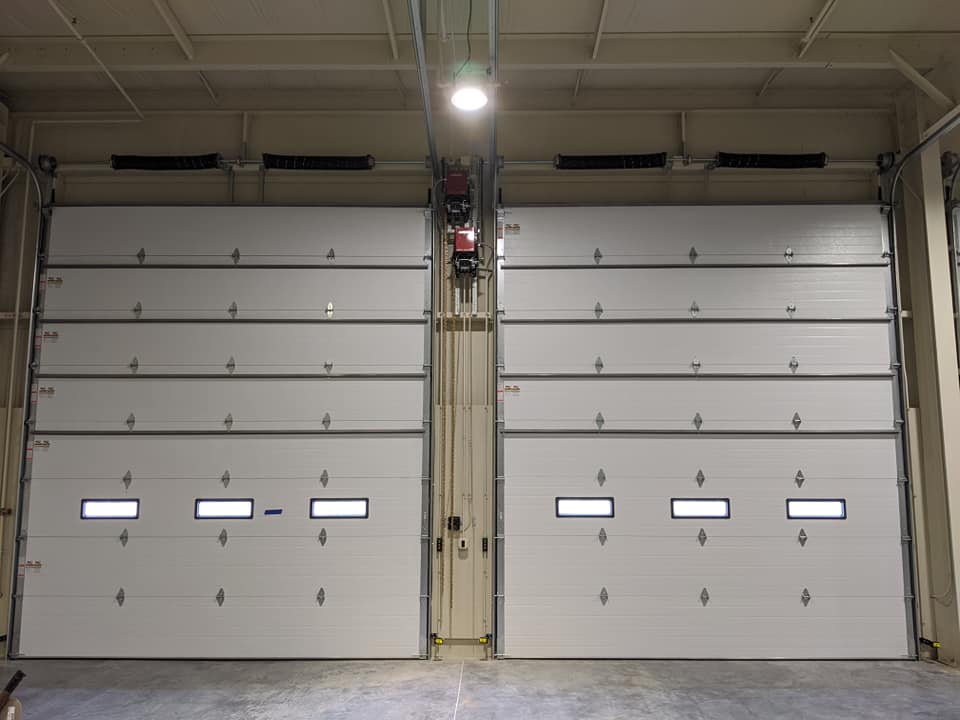 Two white garage doors are open in a building.