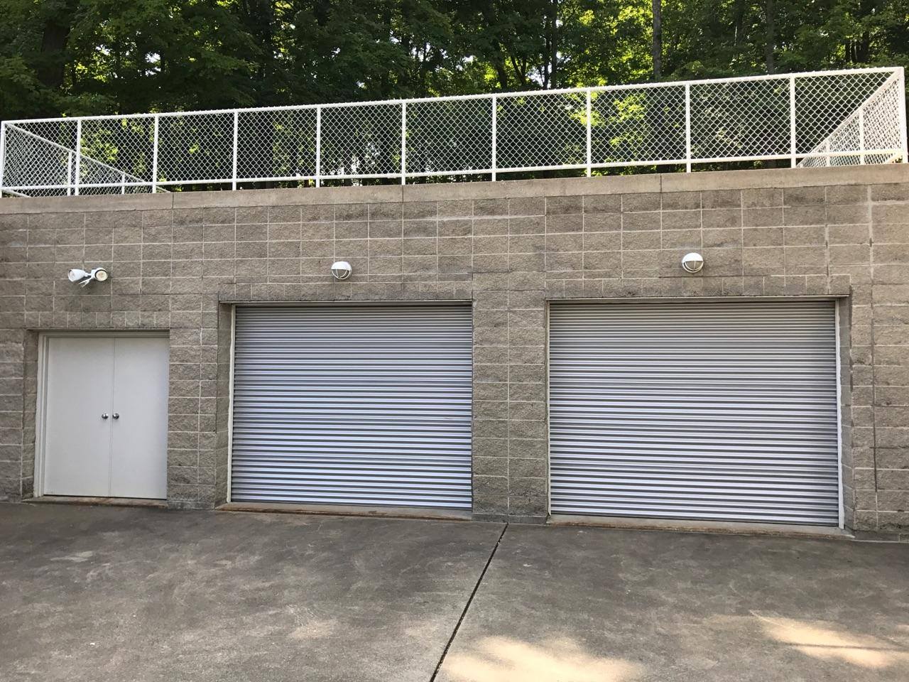 A brick building with two garage doors and a chain link fence.
