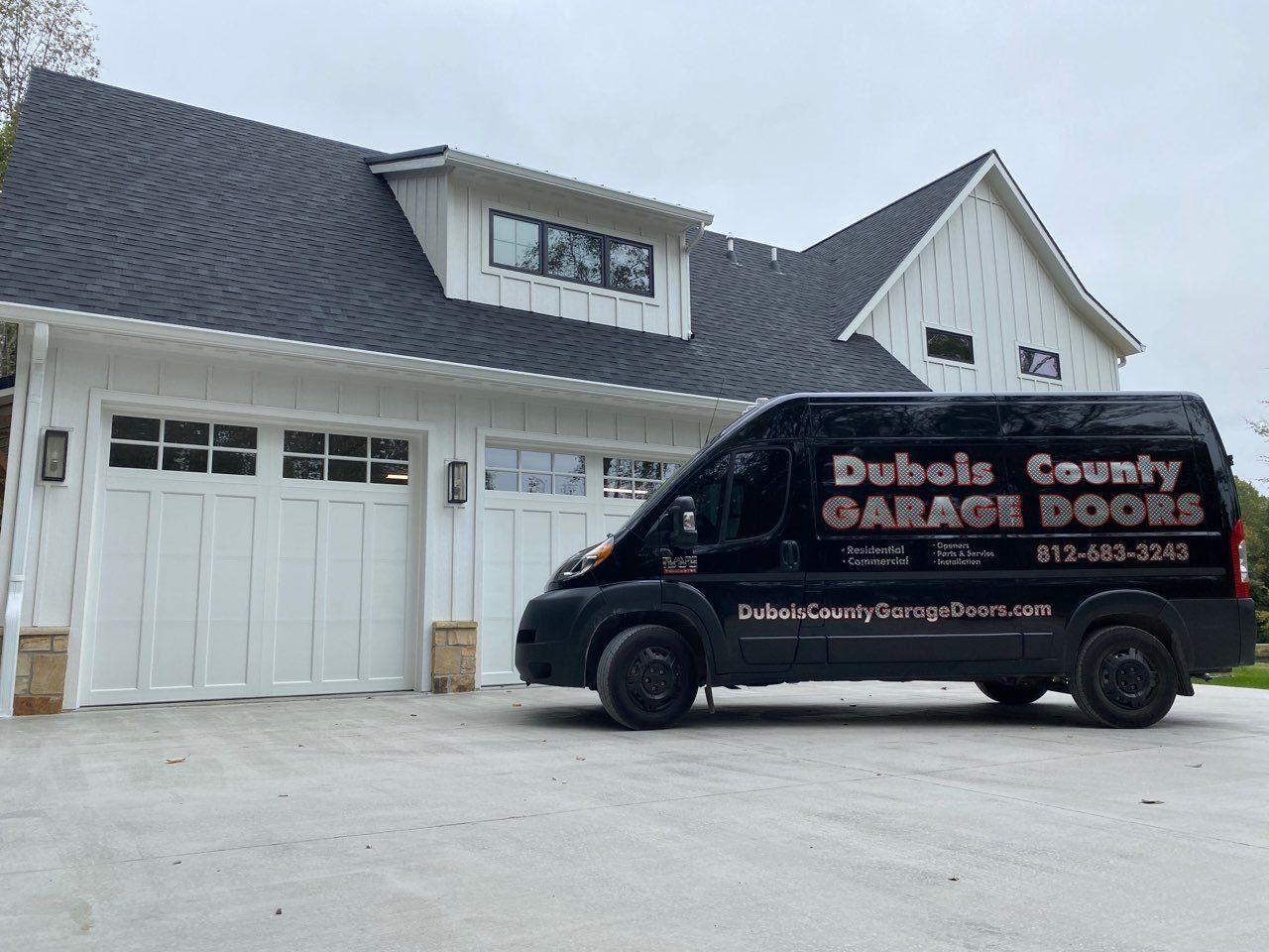 A dubois county garage doors van is parked in front of a white house.