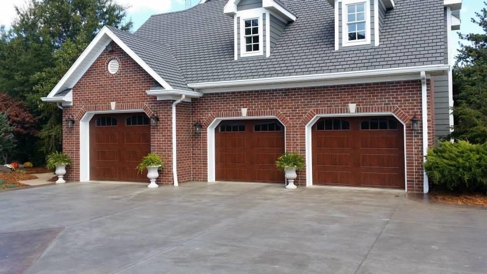 A large brick house with three garage doors and a driveway.