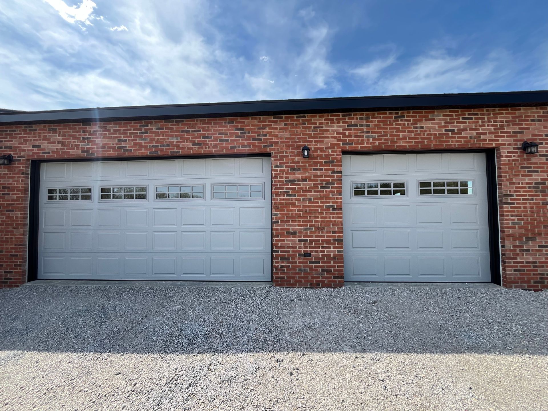 There are two garage doors on a brick building.