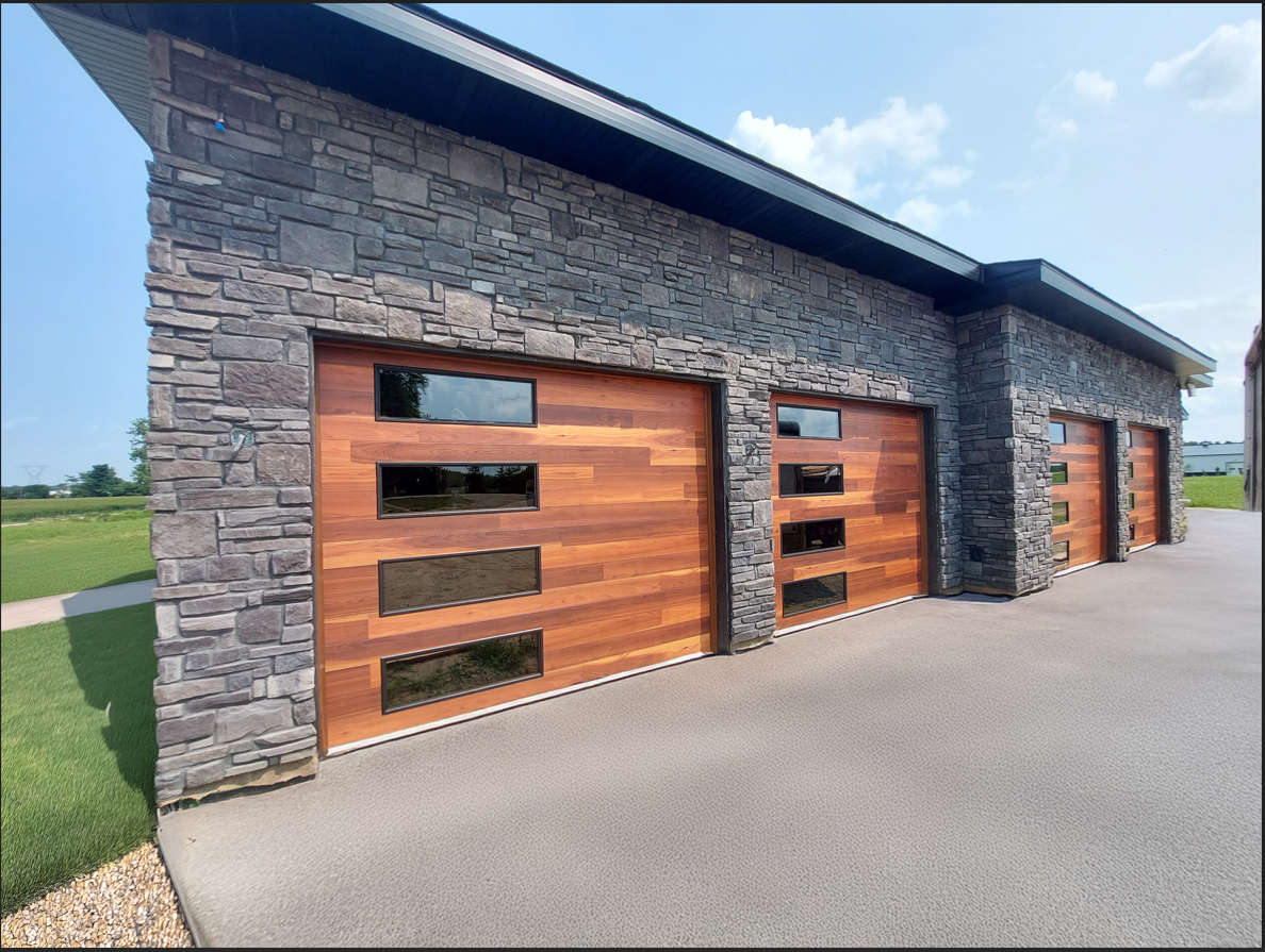 A modern garage with wooden garage doors and a stone wall.