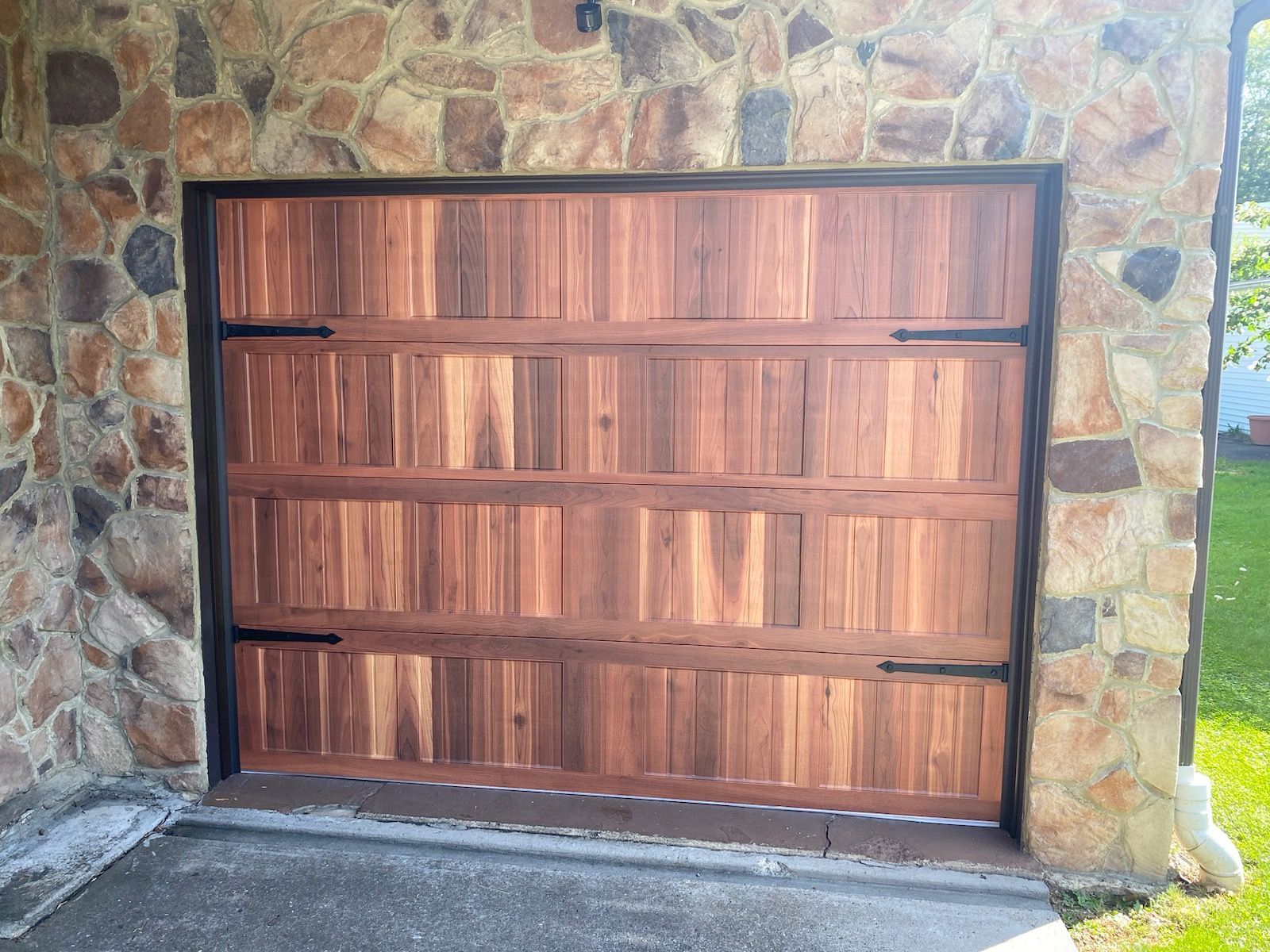 A wooden garage door is against a stone wall