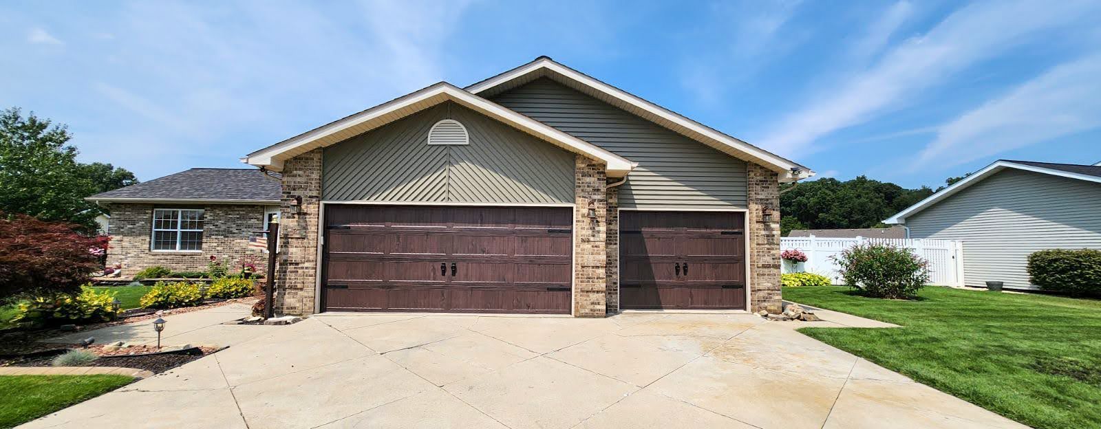 A house with two garage doors and a driveway in front of it.