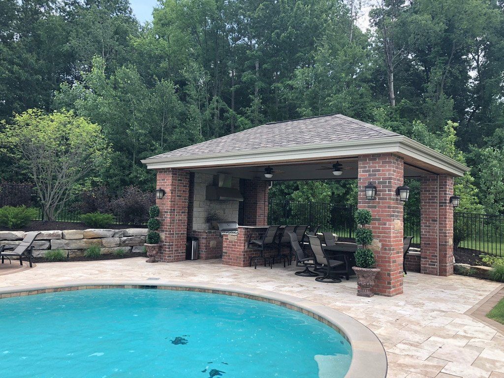 A large swimming pool with a brick pavilion in the backyard.