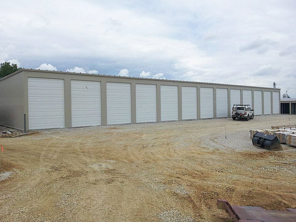 A row of garage doors are lined up in a dirt lot.