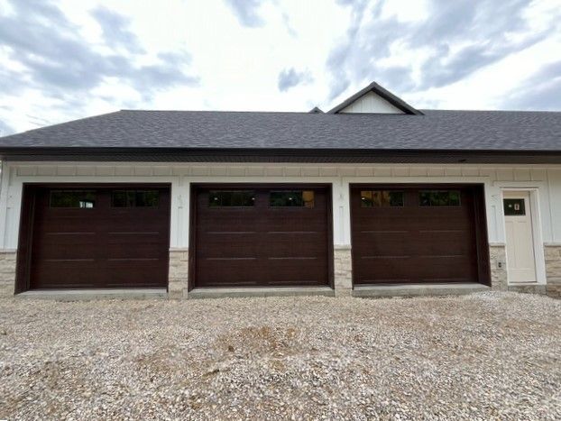 There are three garage doors on the side of a house.