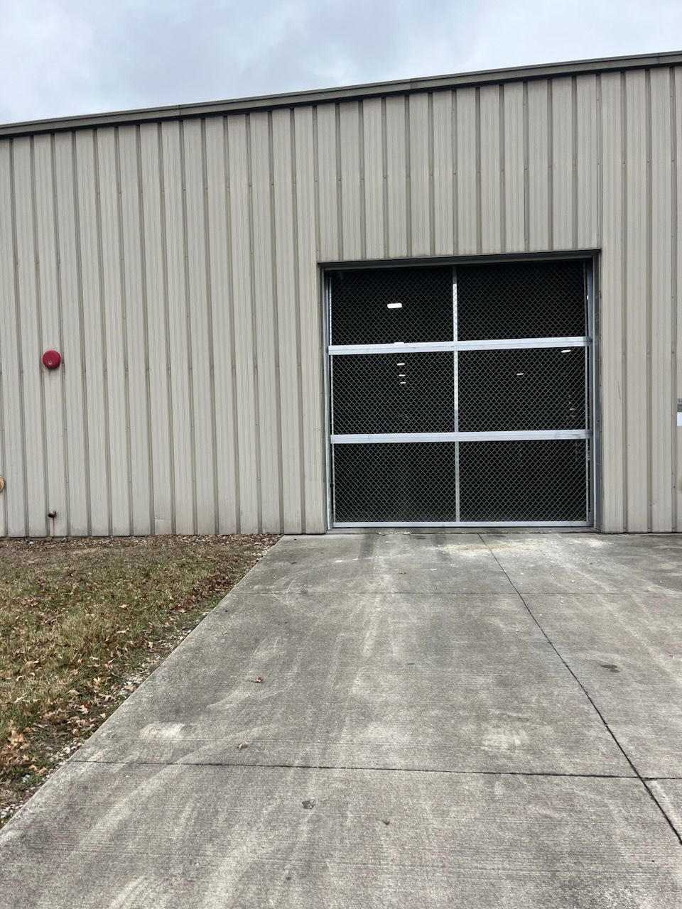 A building with a garage door and a concrete driveway leading to it.