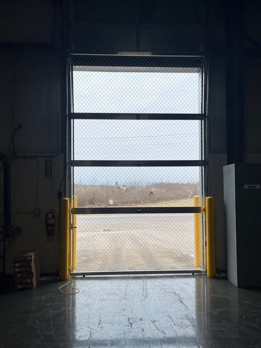 A garage door is open and looking out to a dirt road.