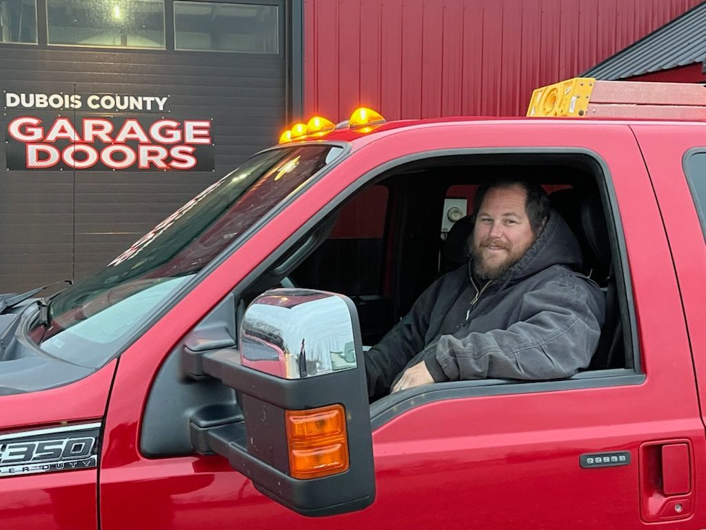 A man is sitting in the driver 's seat of a red truck.