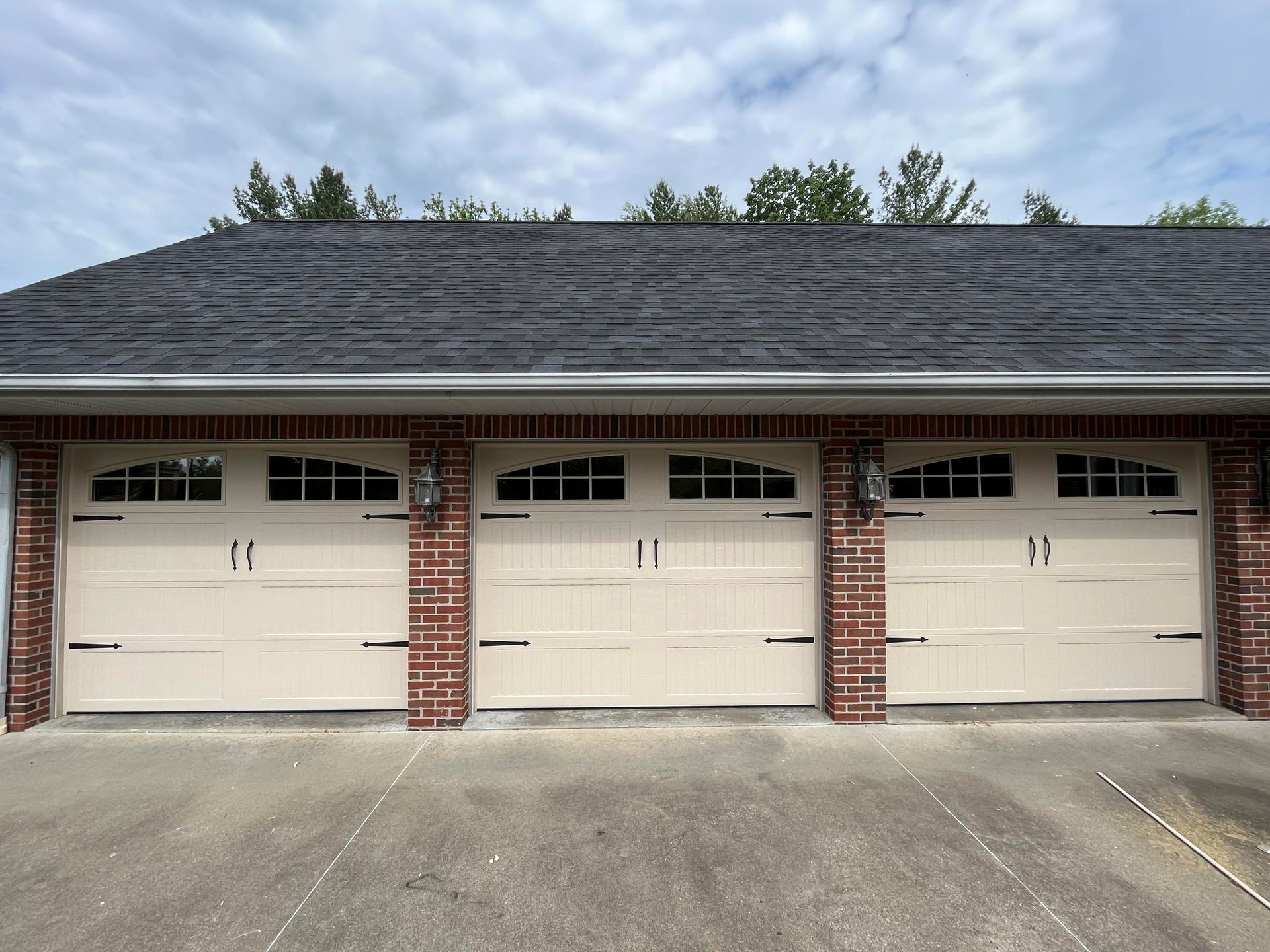 A row of white garage doors on a brick building
