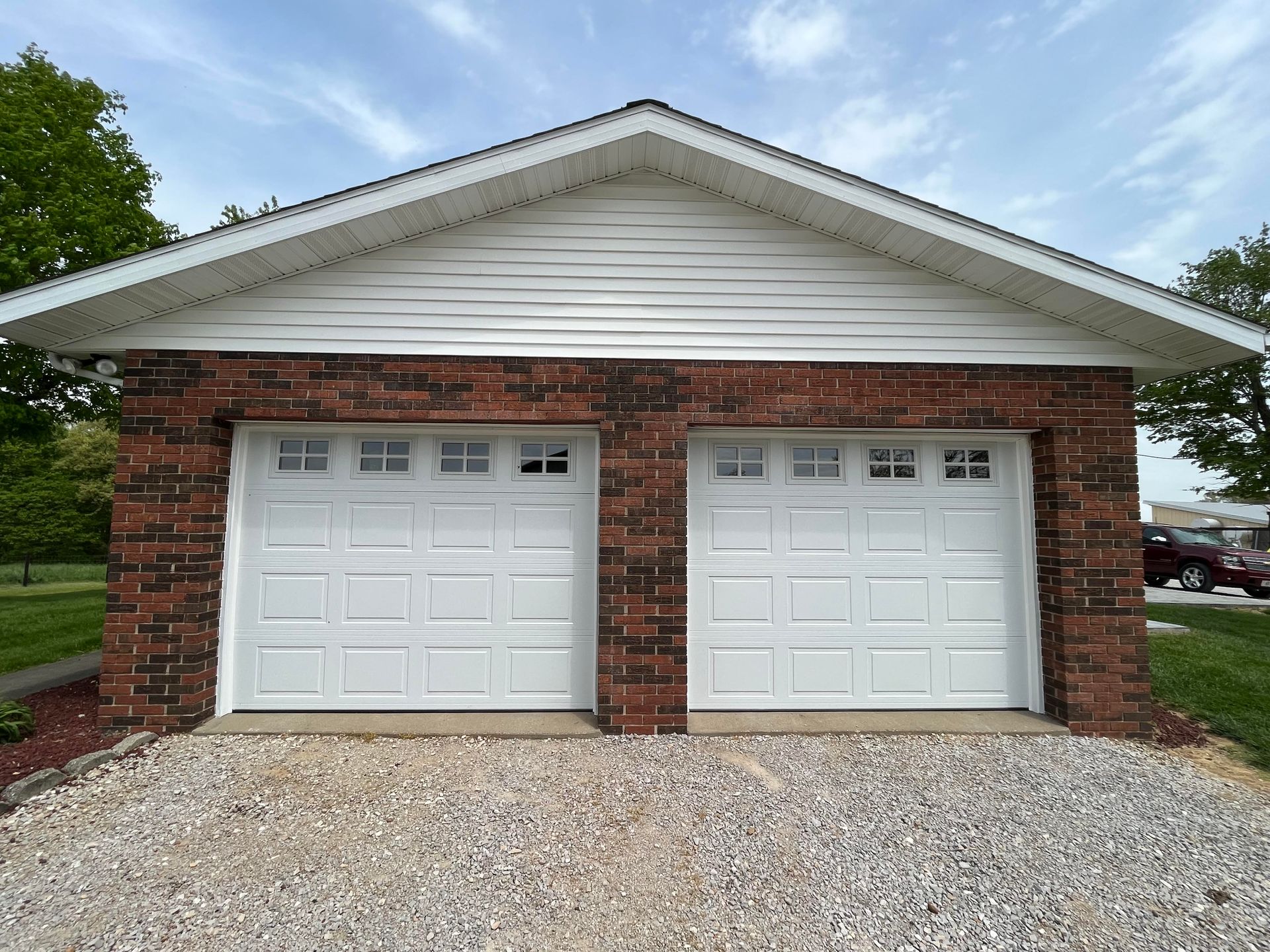 A garage with two white garage doors and a brick wall.