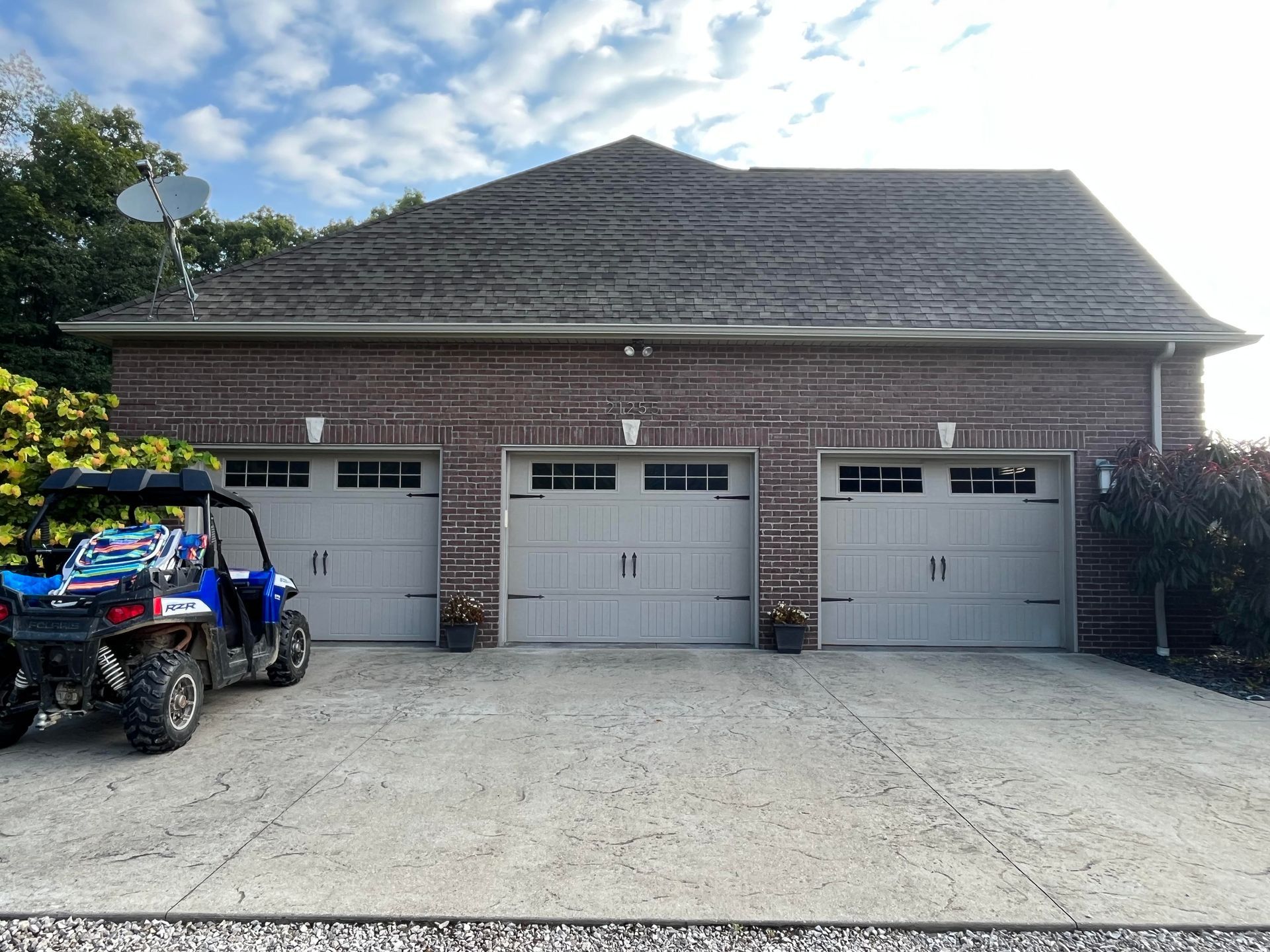 A blue atv is parked in front of a garage.