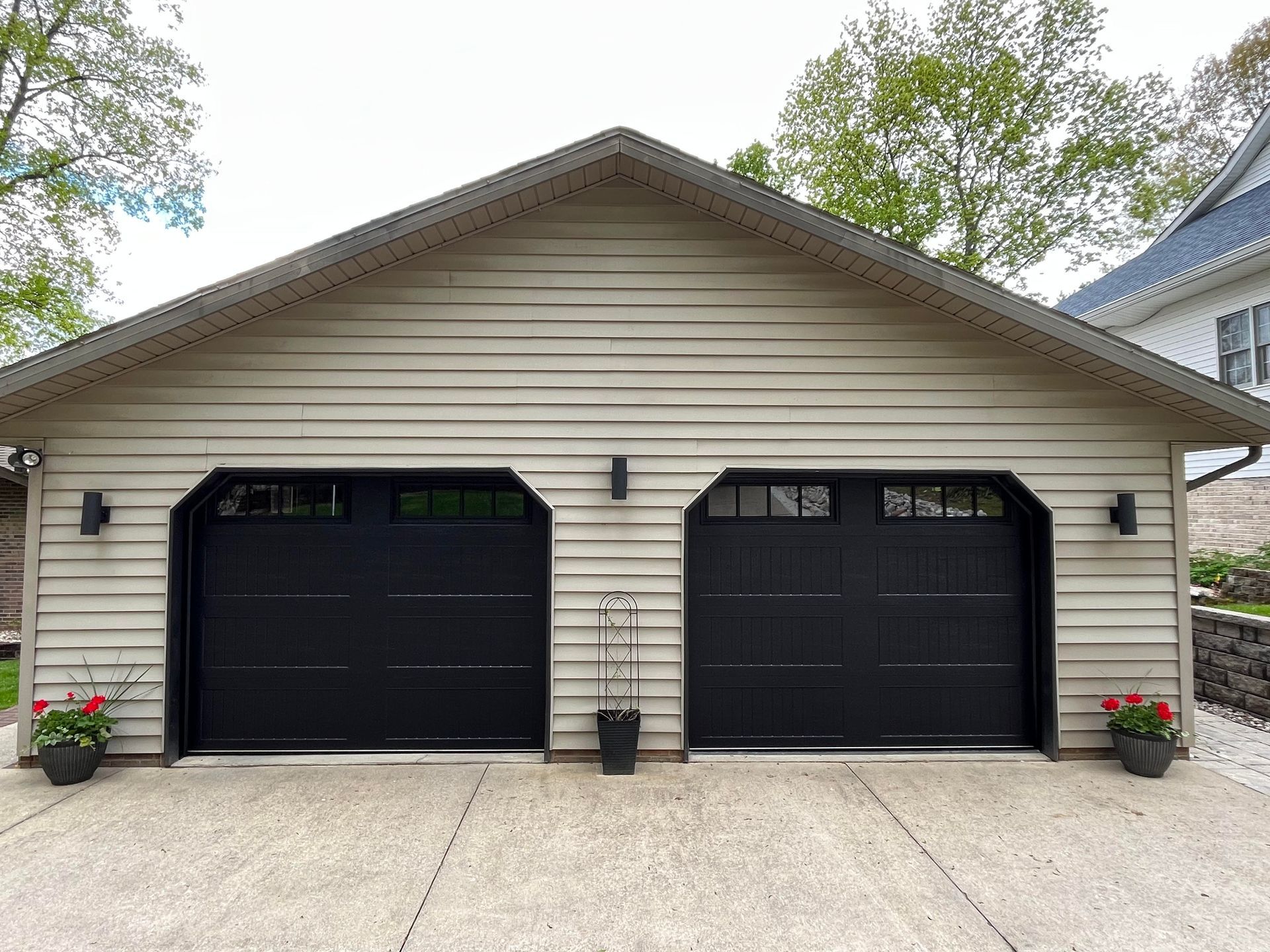 There are two black garage doors on the side of a house.