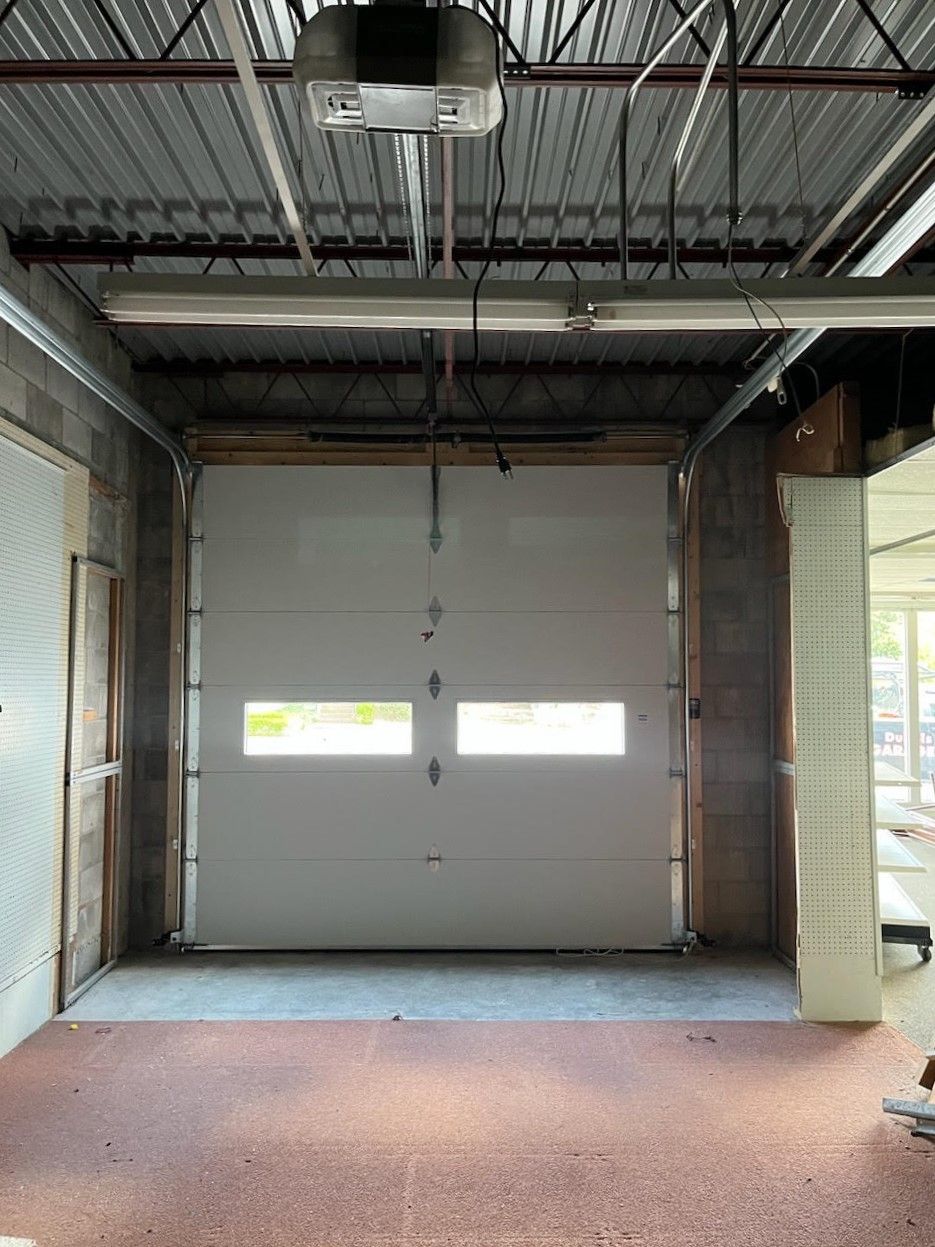 An empty garage with a garage door open and a ceiling fan.