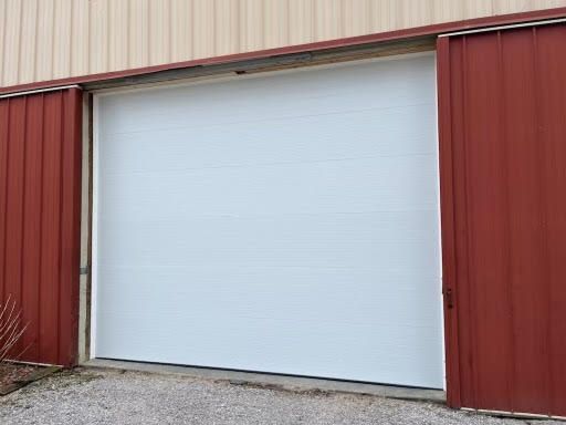 A white garage door is open on a red building.