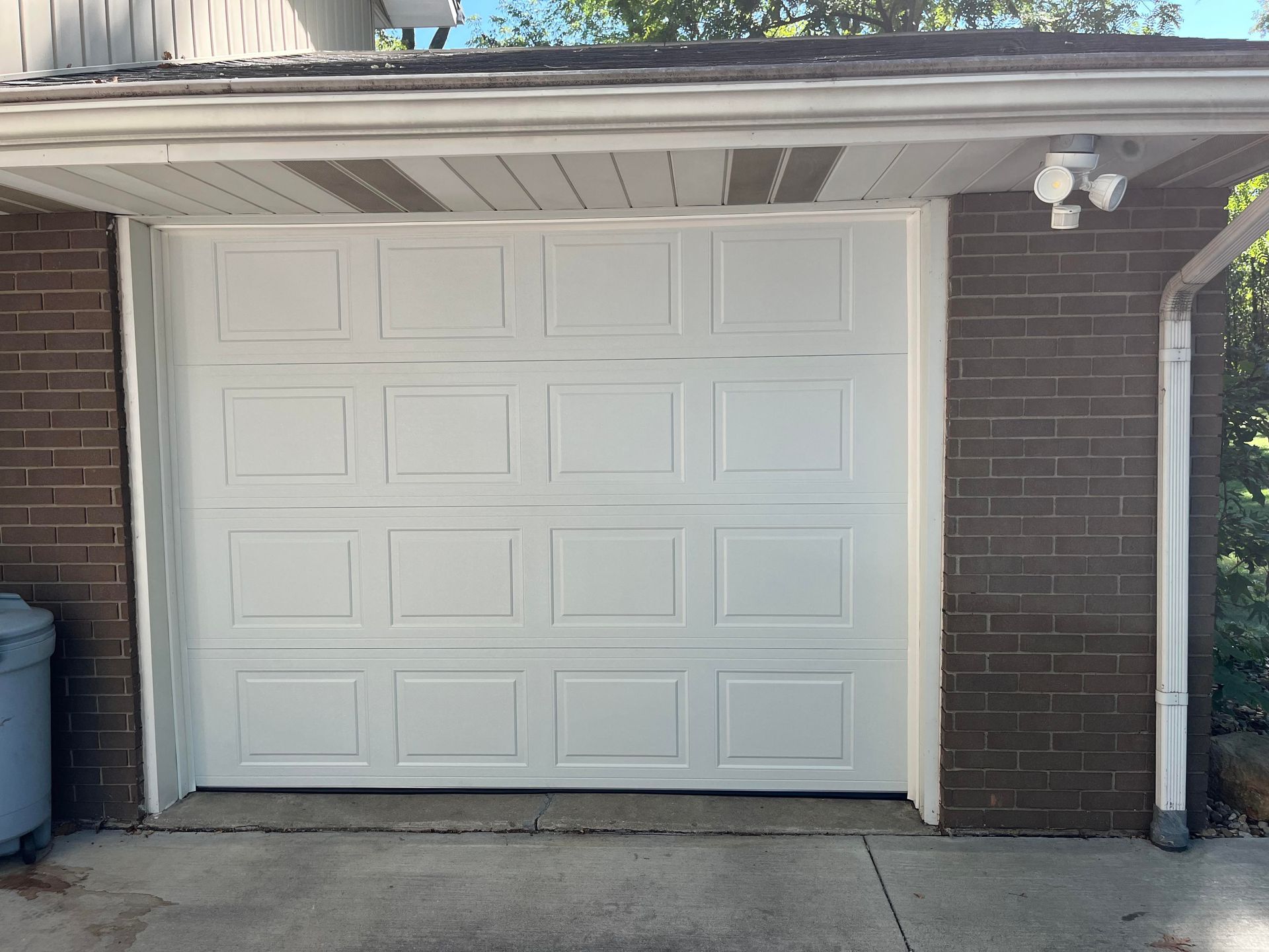 A white garage door is sitting on top of a brick building.