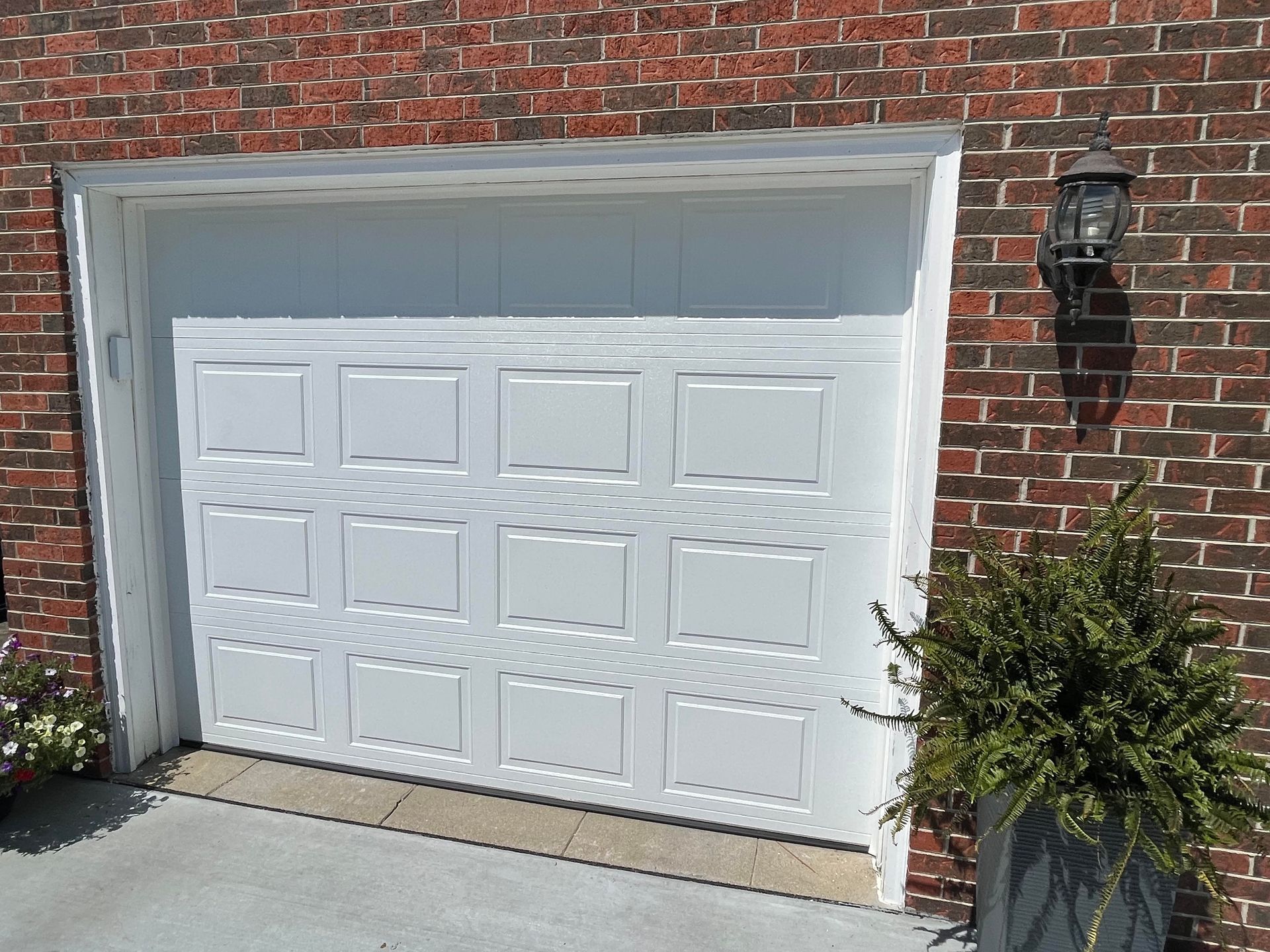 A white garage door is sitting in front of a brick building.