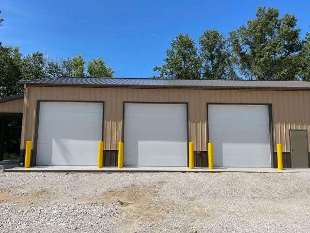 A large building with three garage doors and yellow poles.