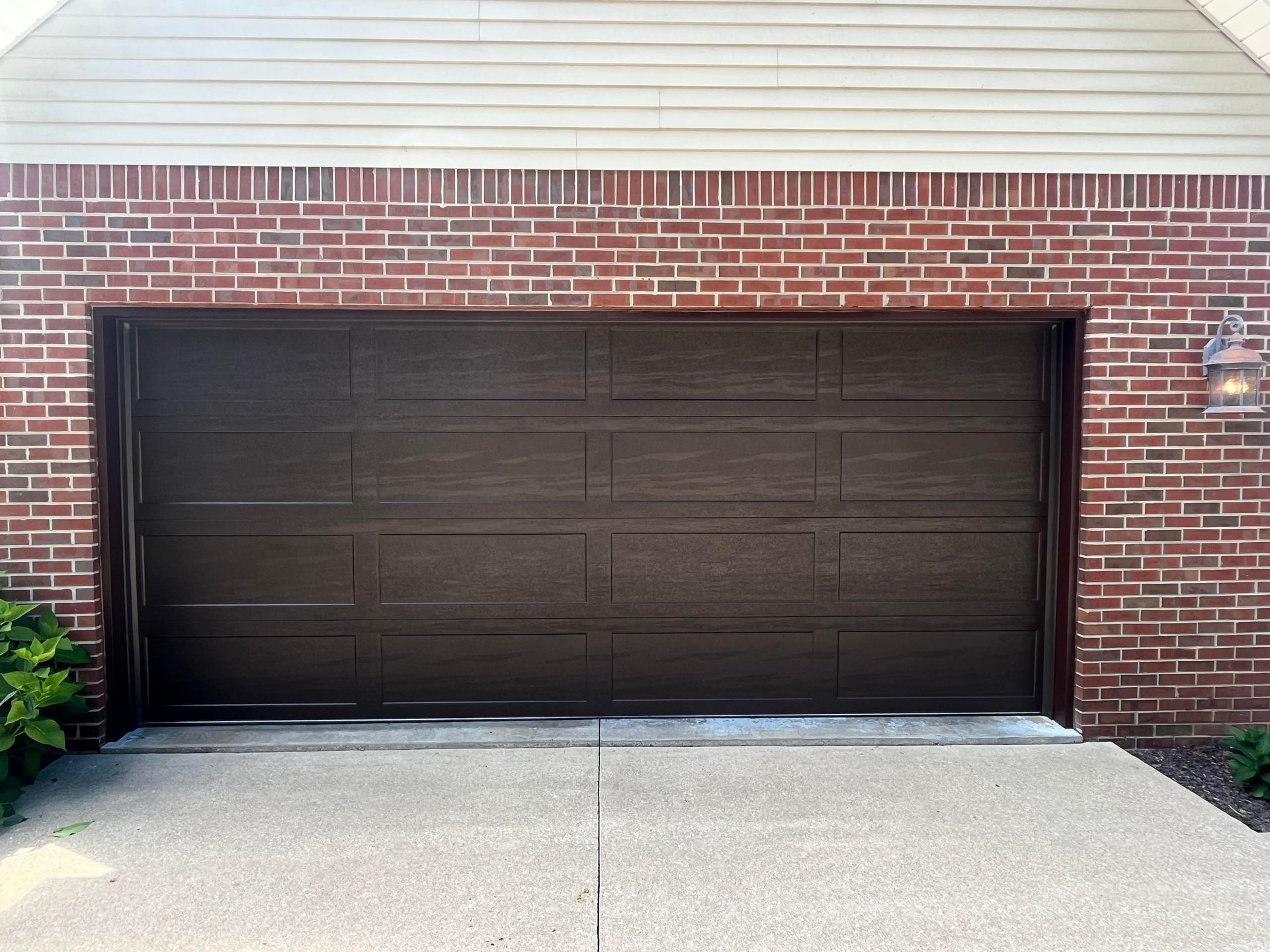 A brick garage with a brown garage door and a concrete driveway.
