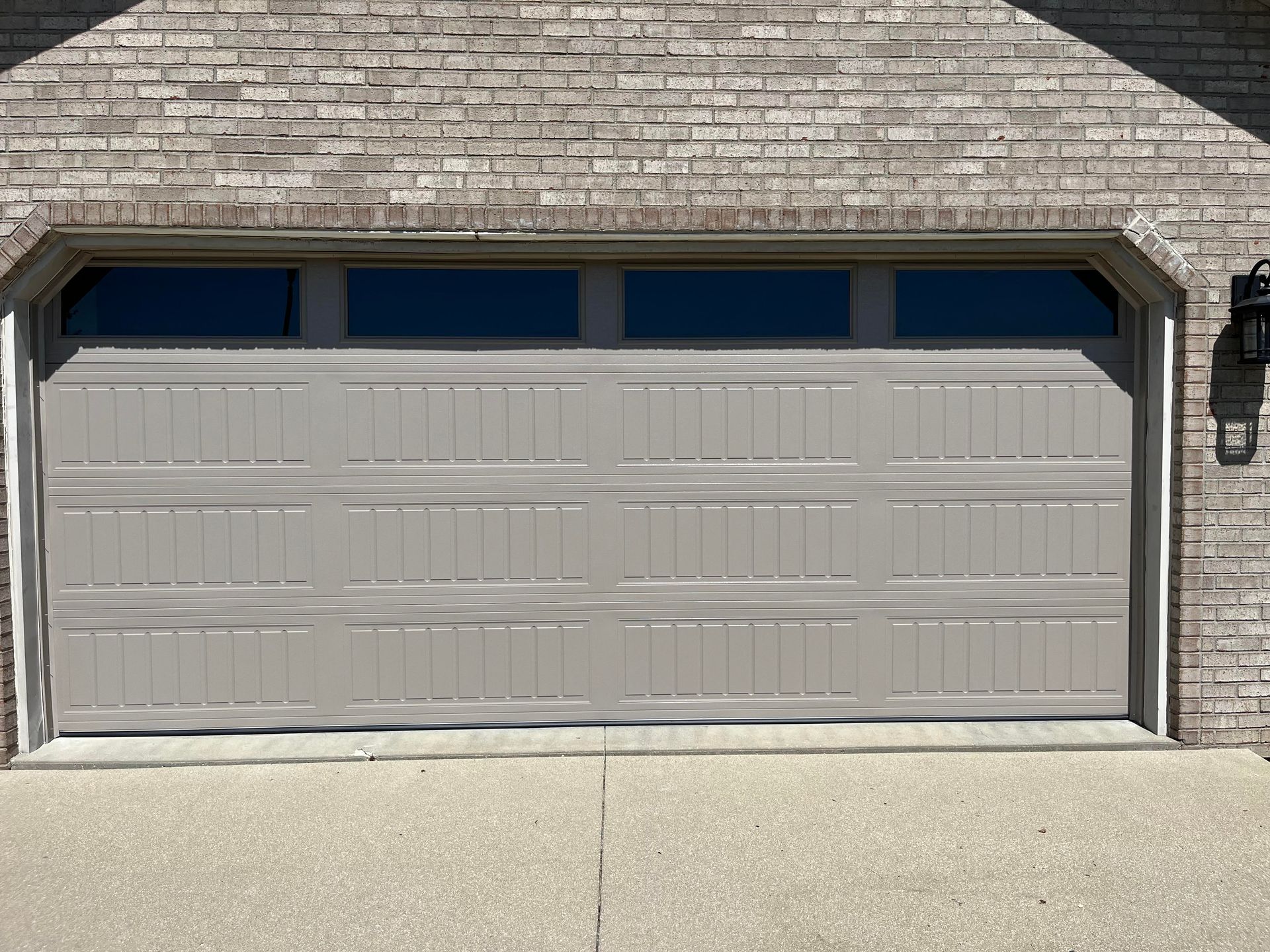 A gray garage door is sitting in front of a brick building.