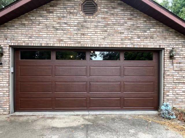 A brown garage door is on a brick building.