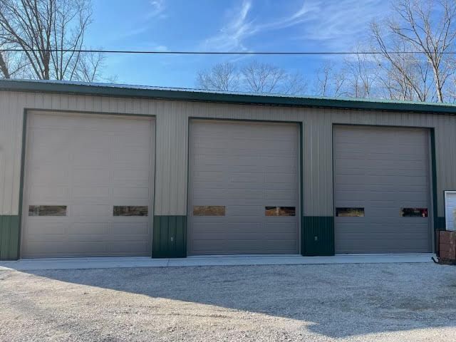 There are three garage doors on the side of a building.