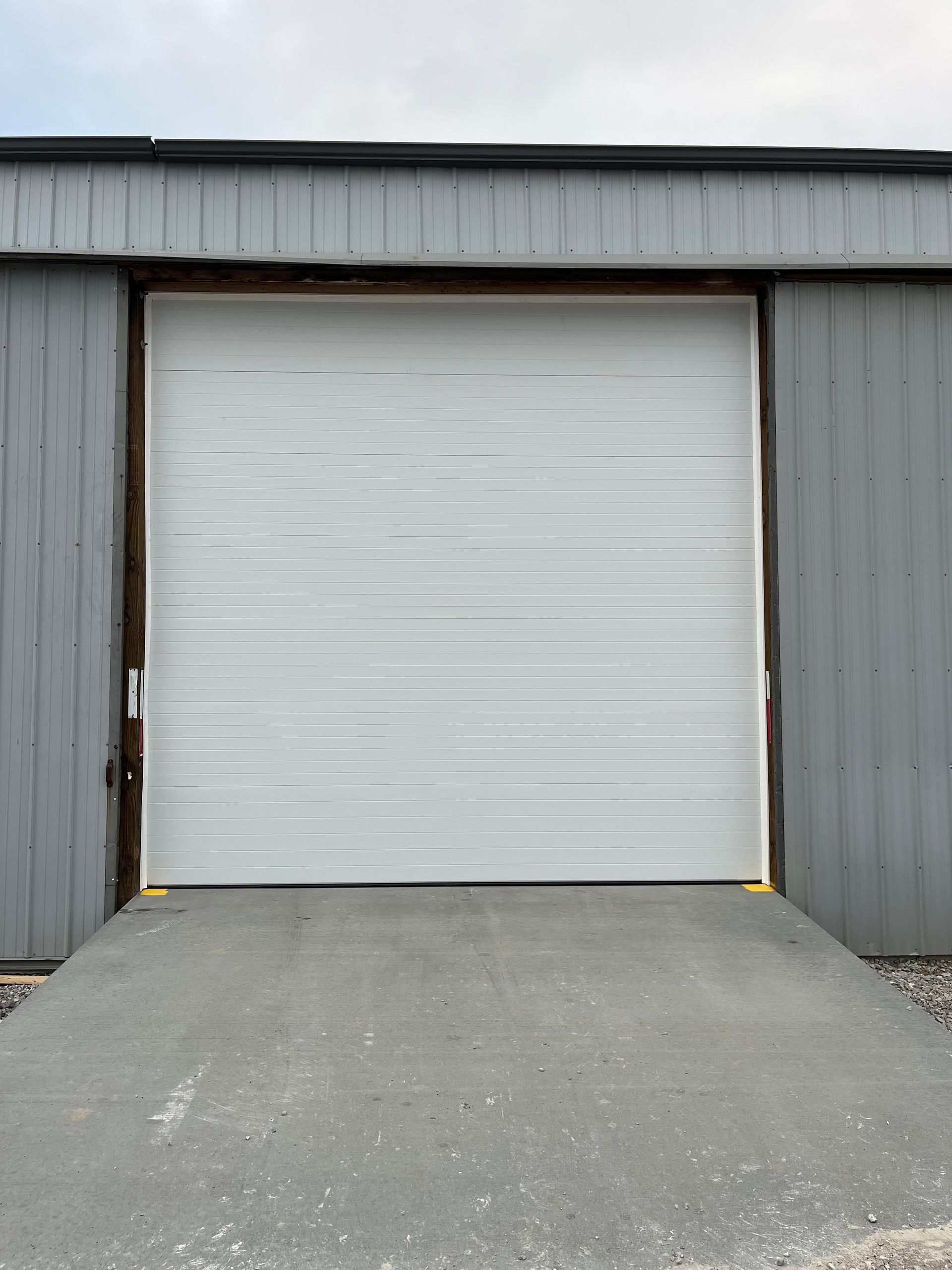 A large white garage door is open on the side of a building.