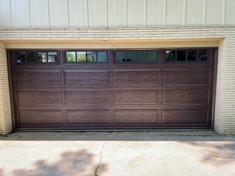 A brown garage door is sitting in front of a white brick building.