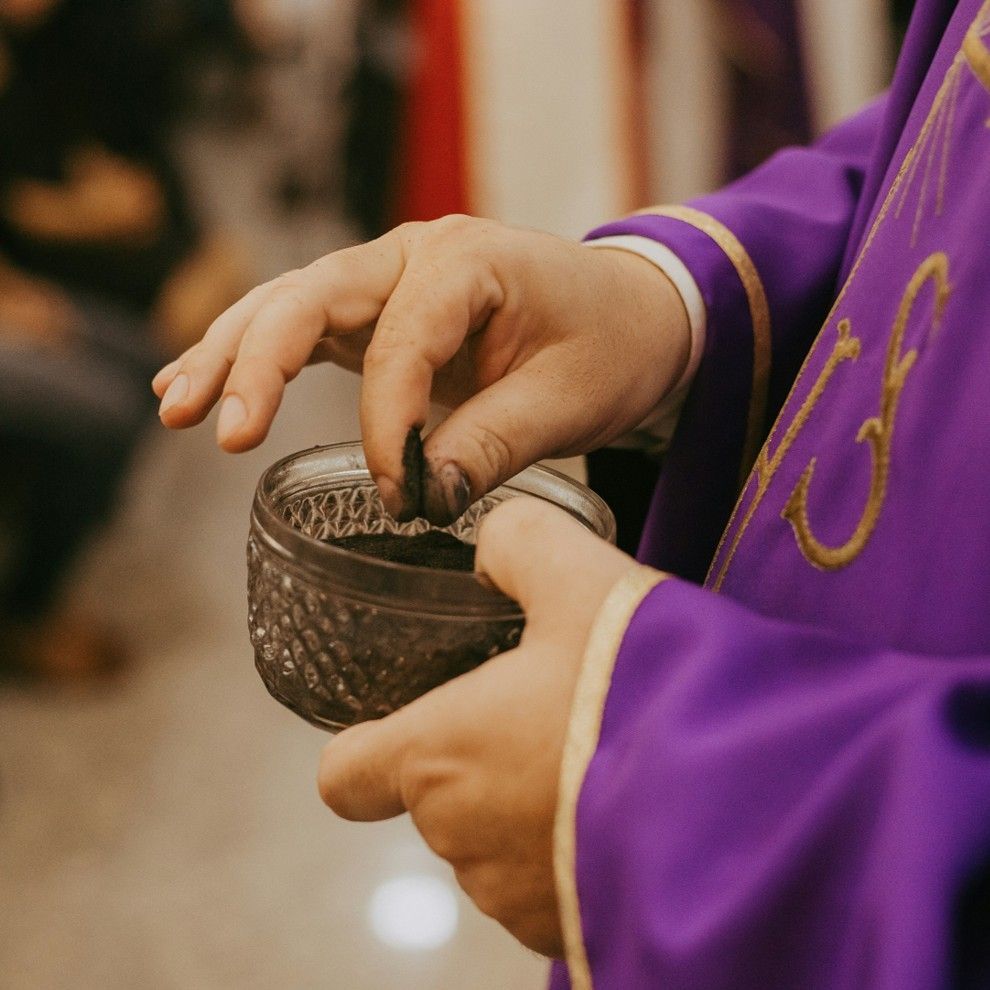 Priest hands holding cup of aches