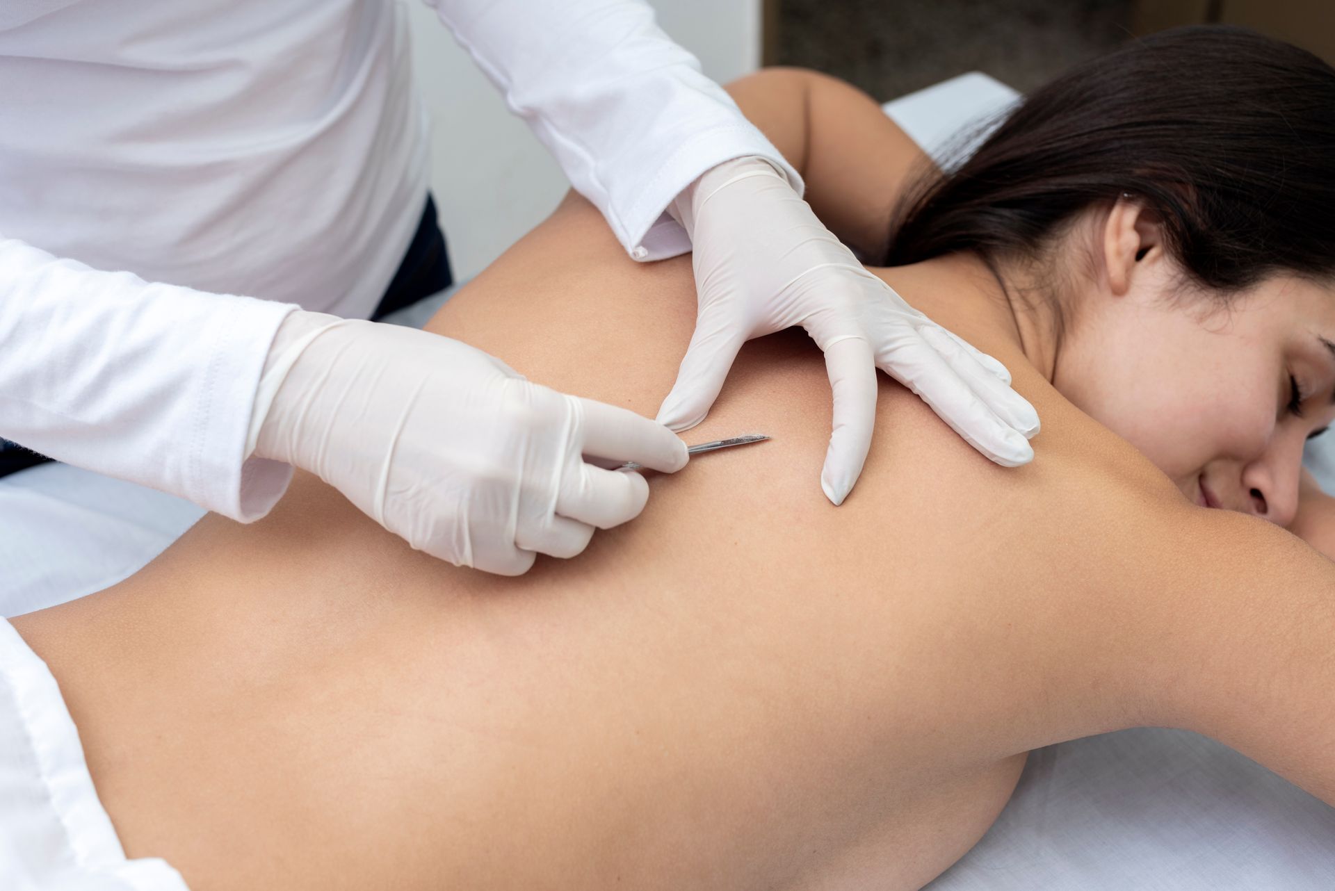 A Woman Is Laying On A Bed Getting A Massage From A Doctor