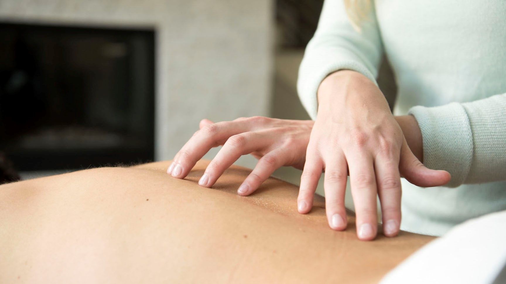A woman is giving a massage to a man 's back.