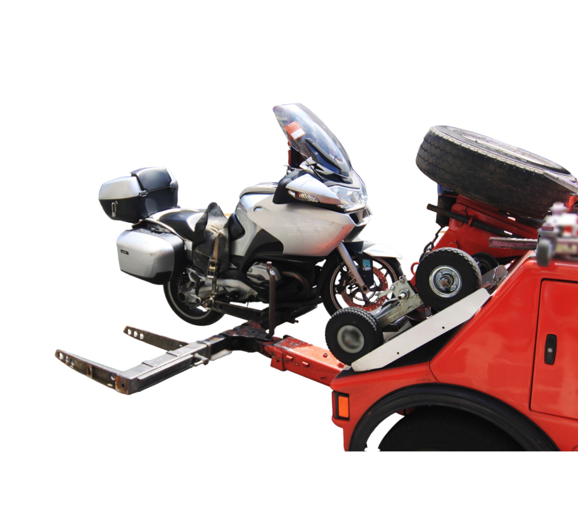A silver touring motorcycle is secured onto the hydraulic lifting arm of a bright red tow truck.