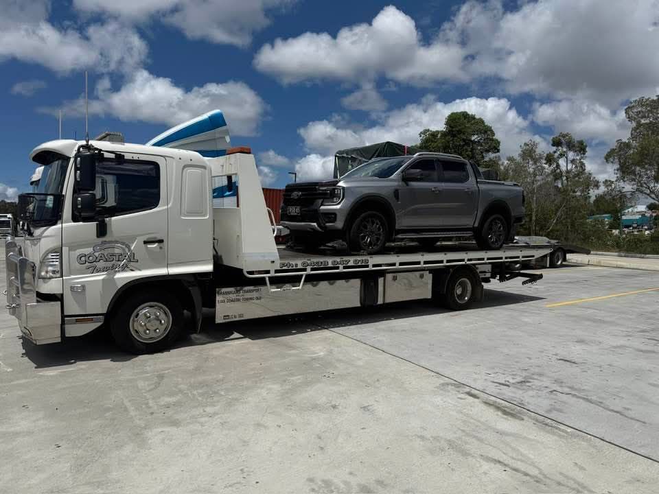 Tow truck with a grey pick up truck on the back.