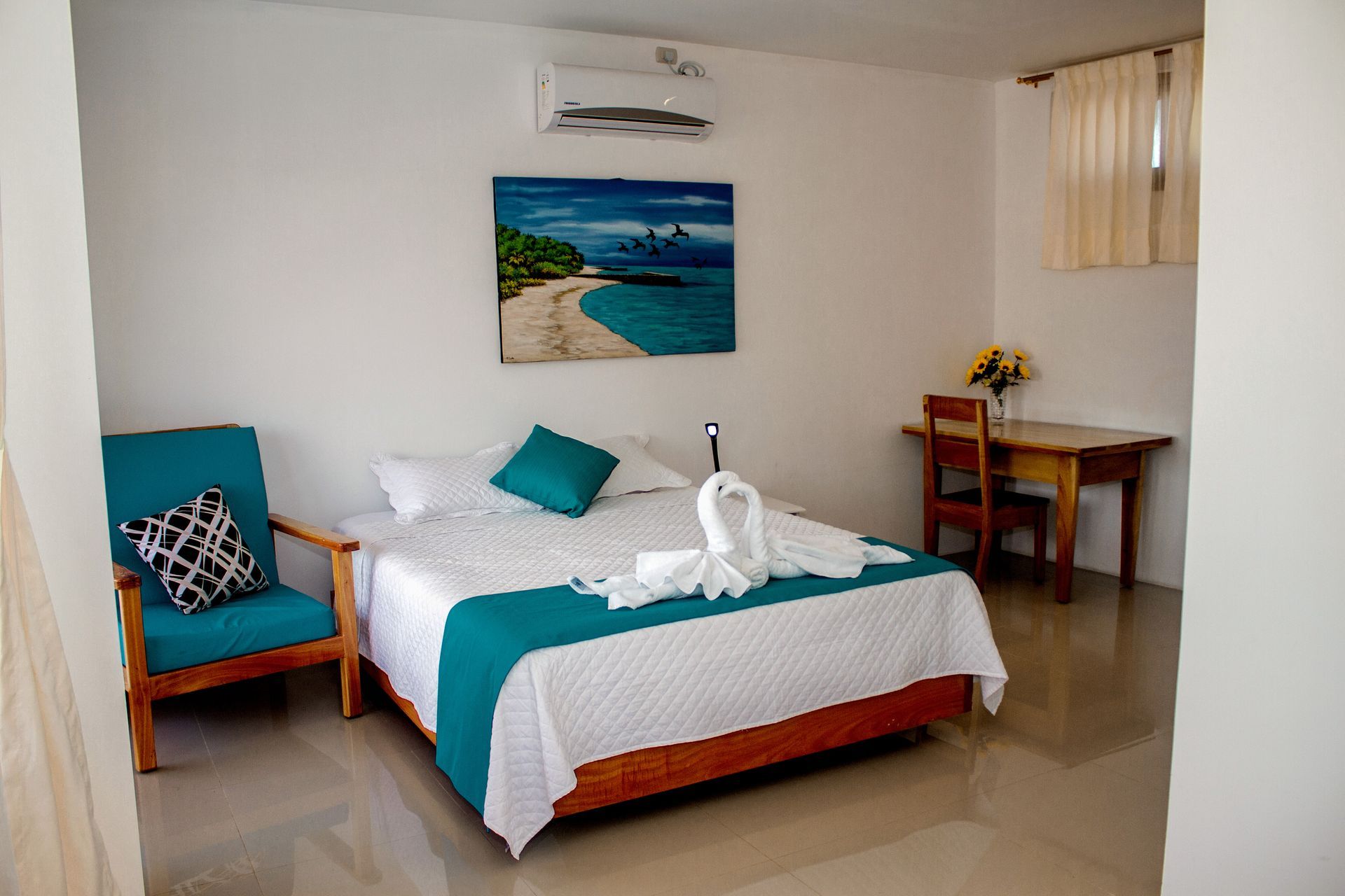 Una habitación de hotel con una cama, una silla, una mesa y un cuadro en la pared.