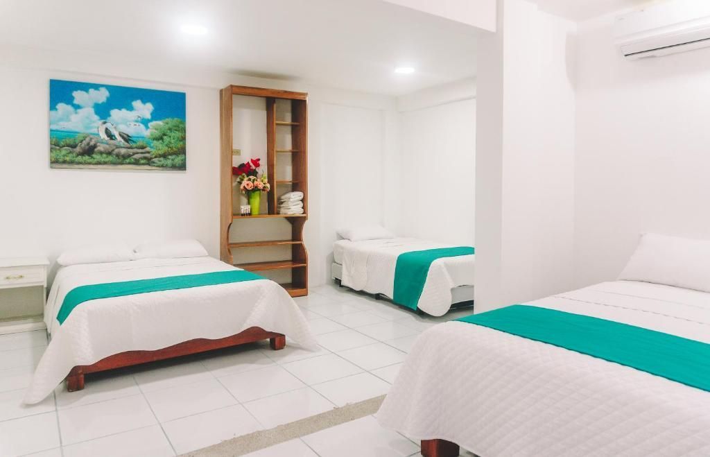 Una habitación de hotel con tres camas y un cuadro en la pared.