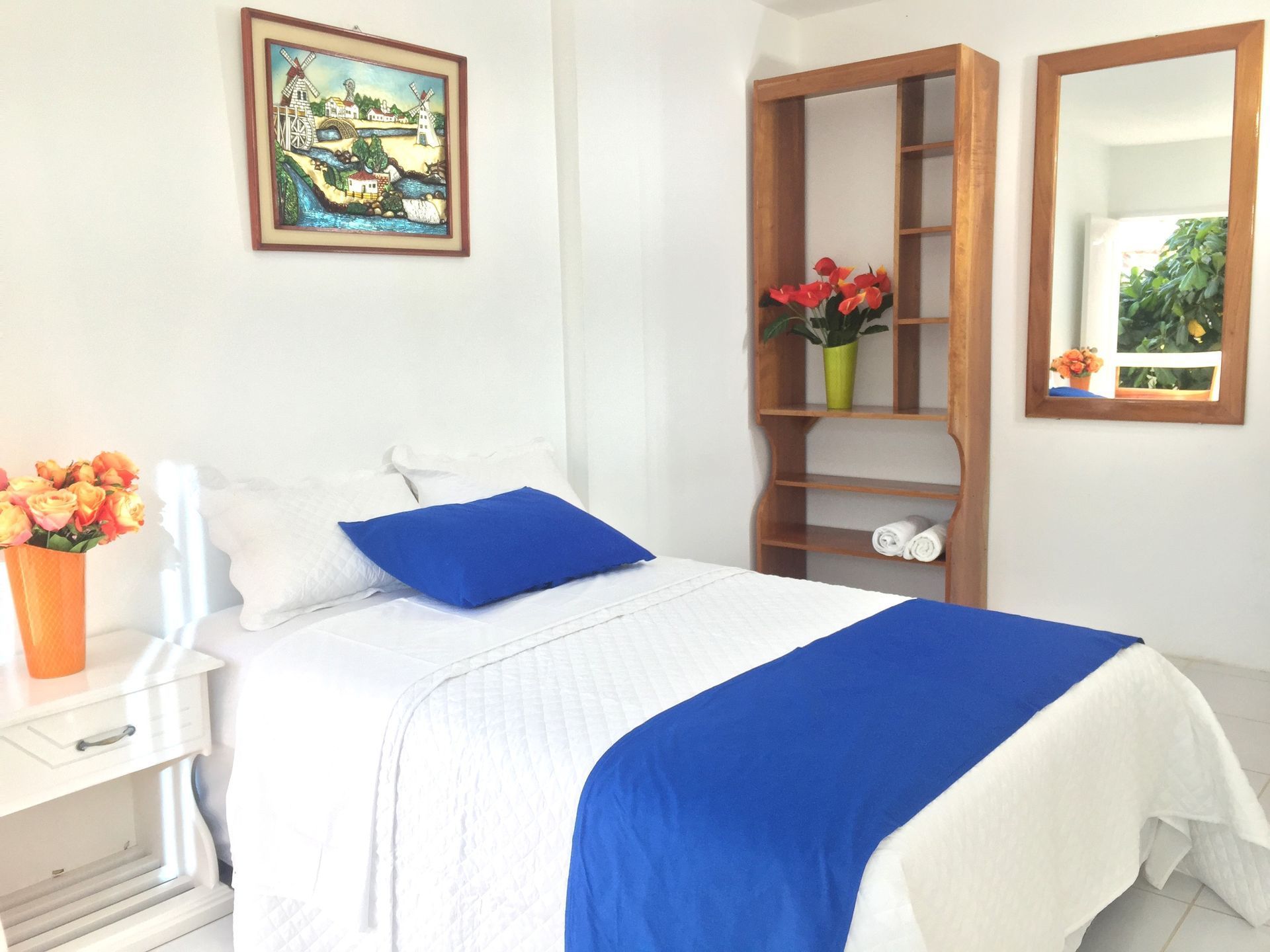 Un dormitorio con una cama, dos espejos y un cuadro en la pared.