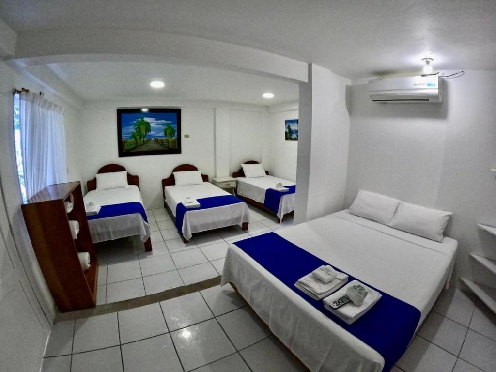 Una habitación de hotel con tres camas y un cuadro en la pared.
