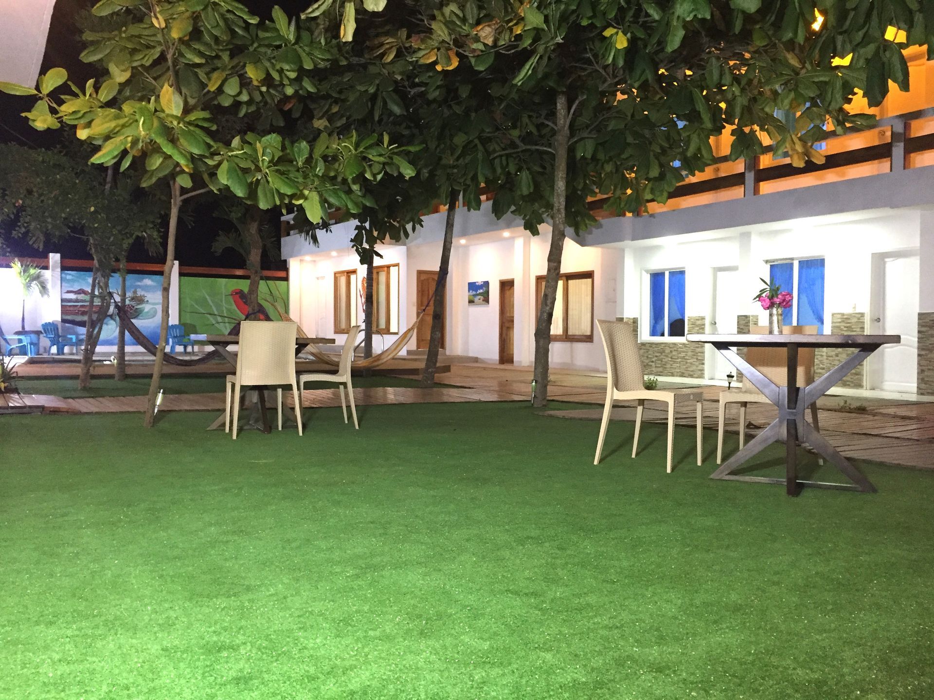 Un césped con mesas y sillas frente a un edificio por la noche.