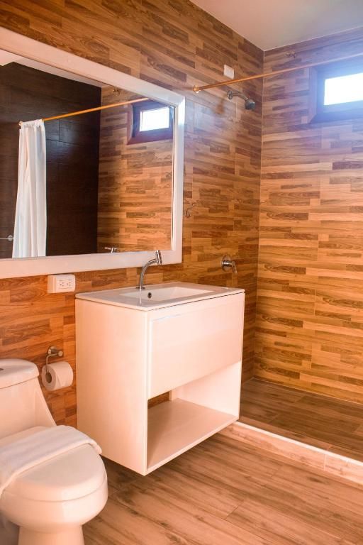 Un baño con inodoro, lavabo, espejo y ducha.
