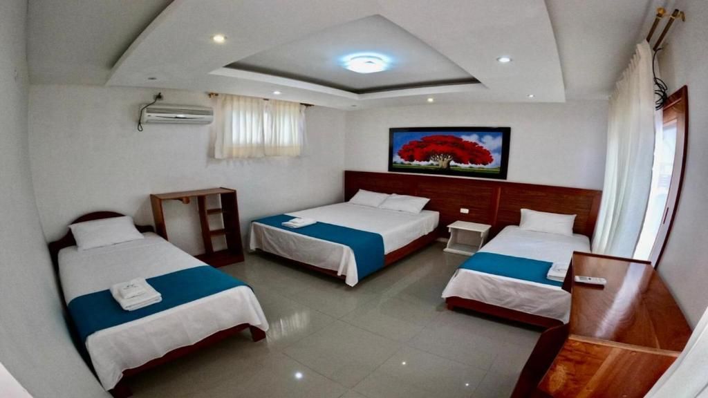 Una habitación de hotel con tres camas y un cuadro en la pared.
